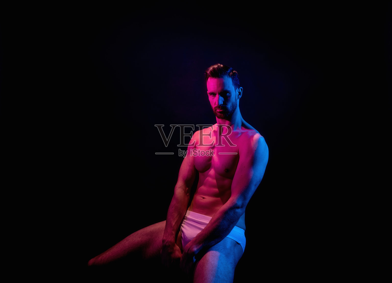 英俊的男子在黑色背景与红色和蓝色照明照片摄影图片