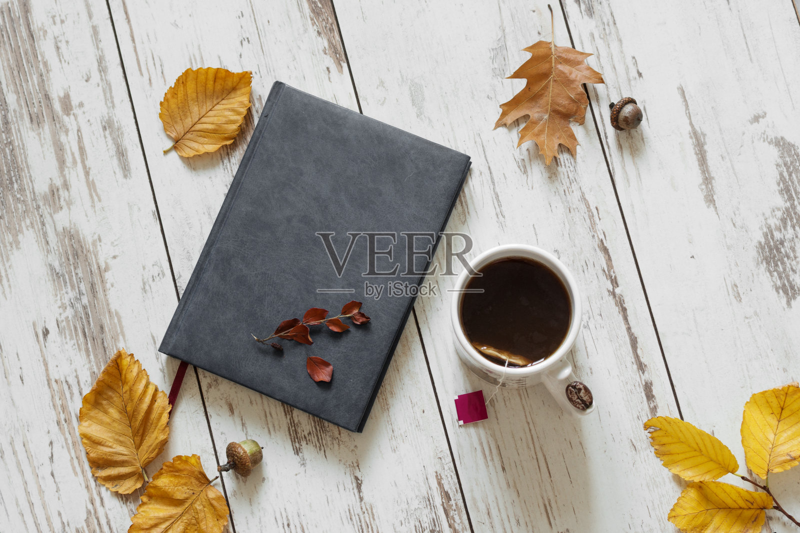 杯茶配书，秋叶在木桌上顶景。照片摄影图片