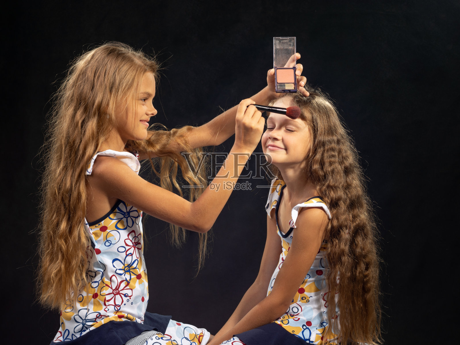 一个女孩把粉抹在另一个女孩的额头上照片摄影图片