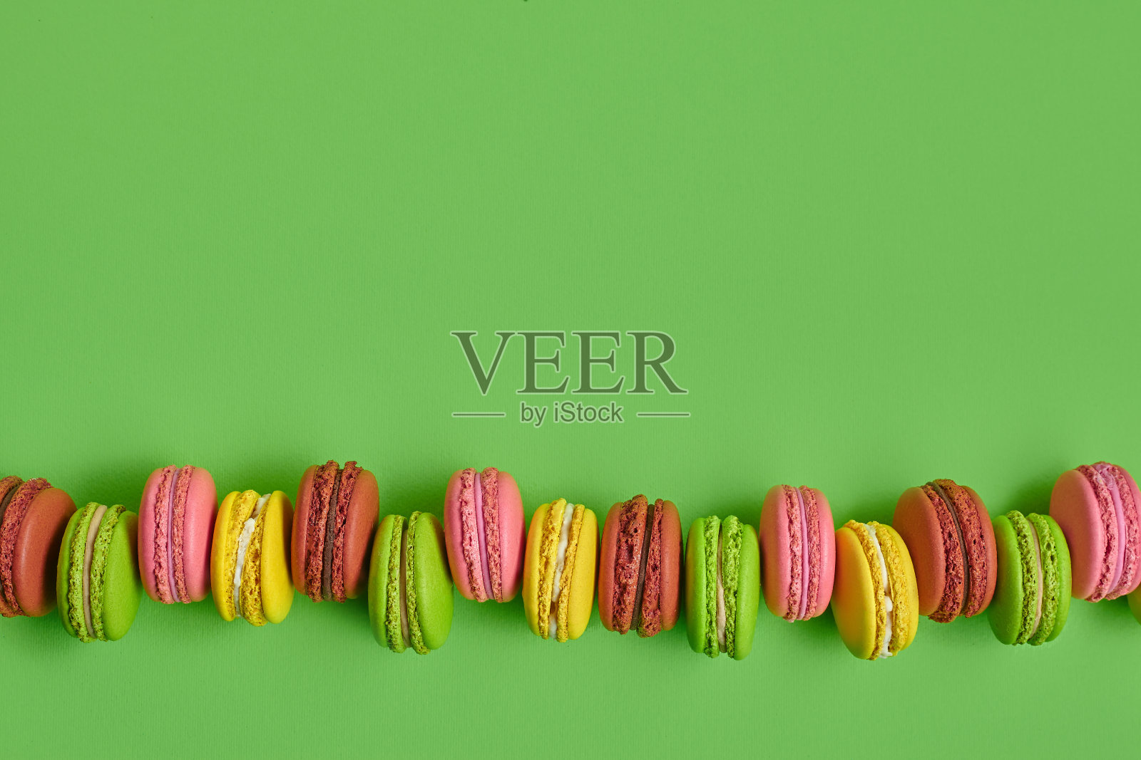 彩色的马卡龙或马卡龙，绿色背景的甜蛋白糖霜为基础的甜点。特写,复制空间照片摄影图片