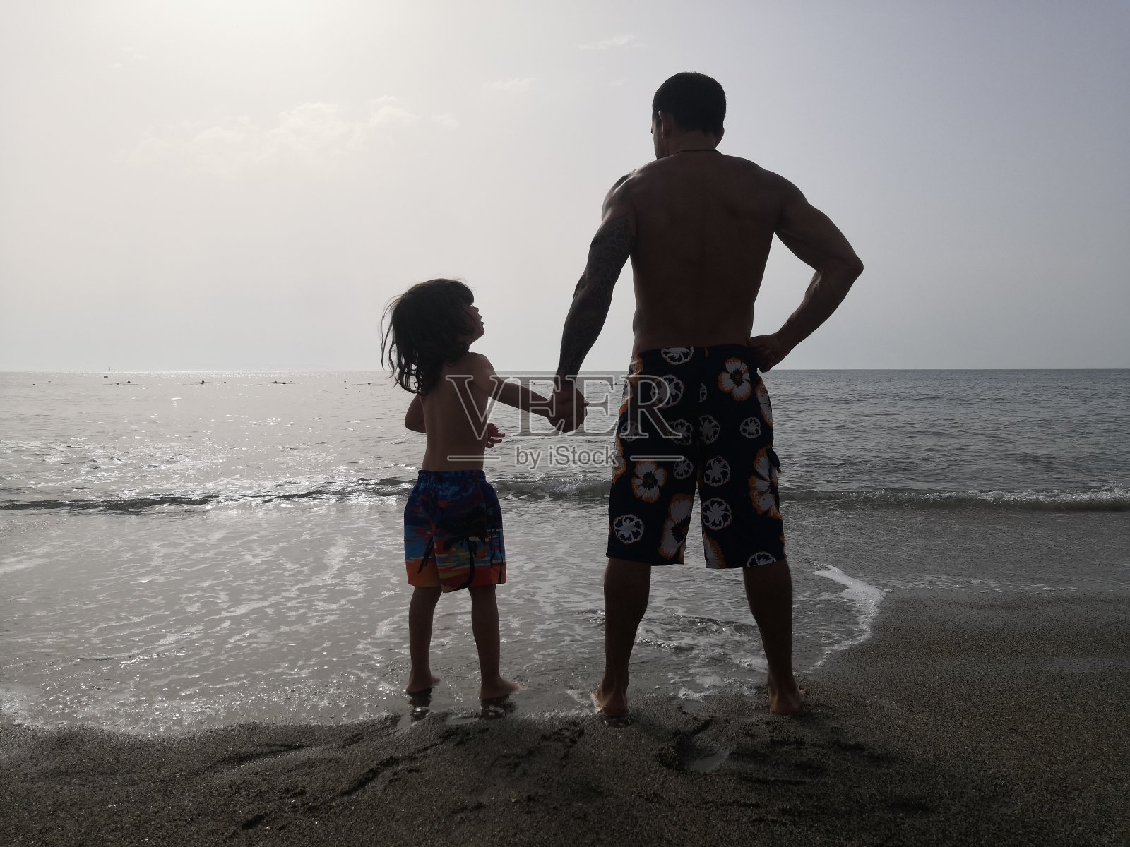 父亲和儿子在海滩上鬼混照片摄影图片