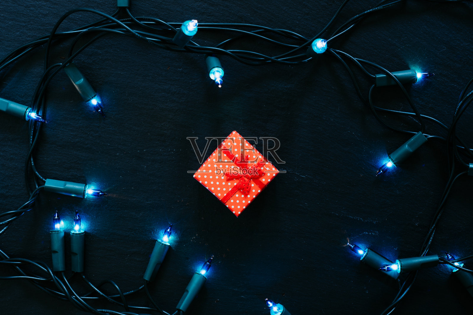 蓝色灯光装置和黑色背景上的红色小礼品盒照片摄影图片