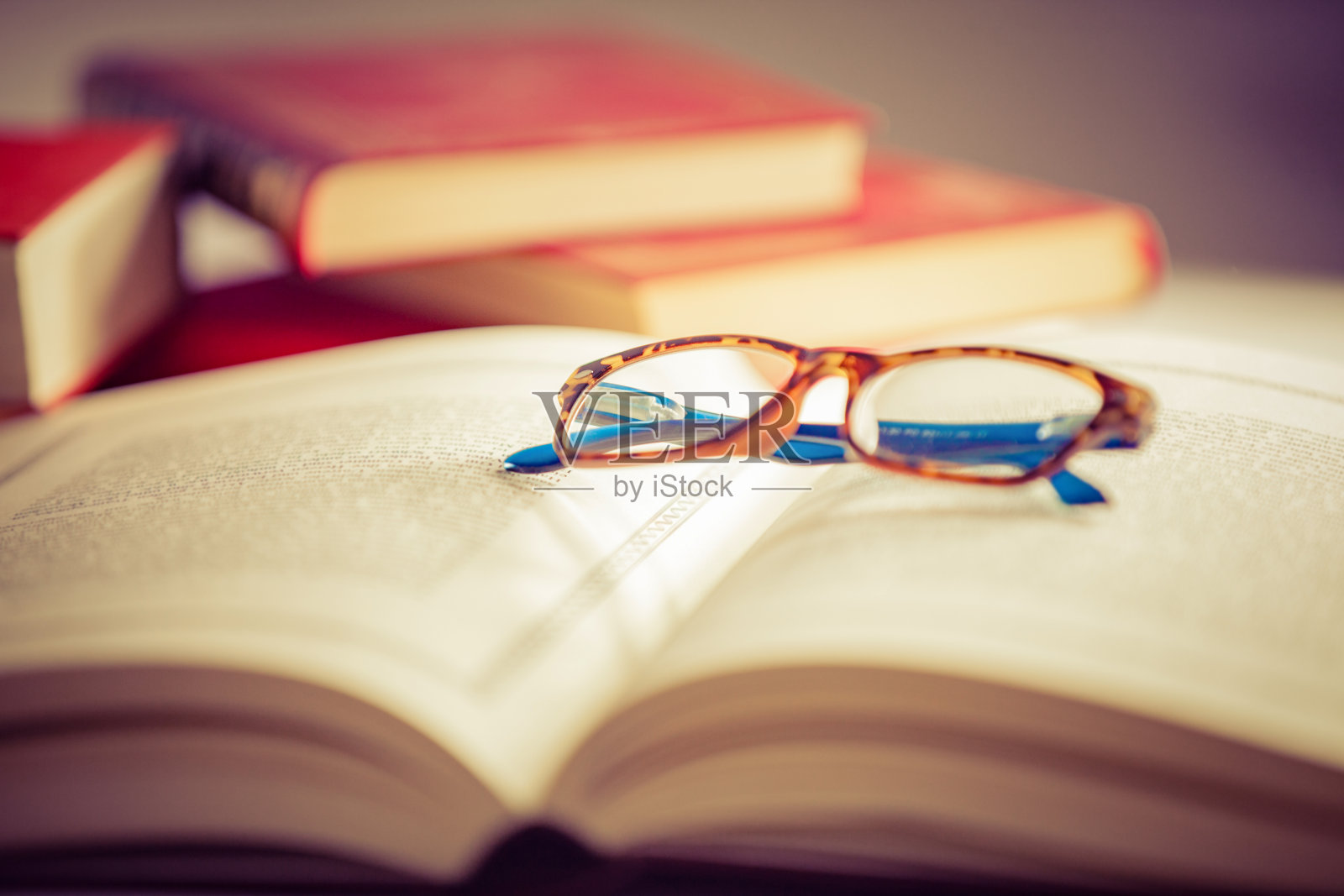 眼镜躺在红色的书上照片摄影图片