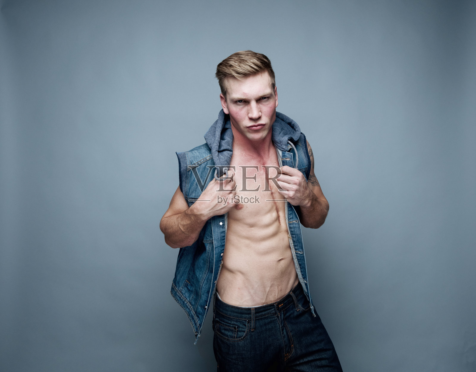 帅气的男人穿着背心，炫耀着他的腹肌照片摄影图片