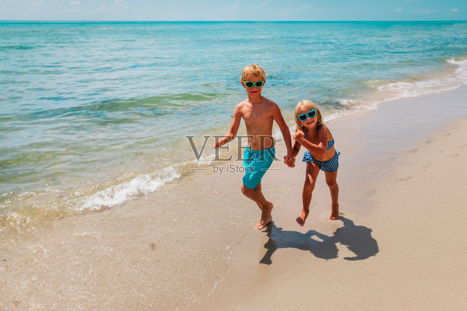 快乐的小女孩和小男孩在海滩上跑步照片摄影图片