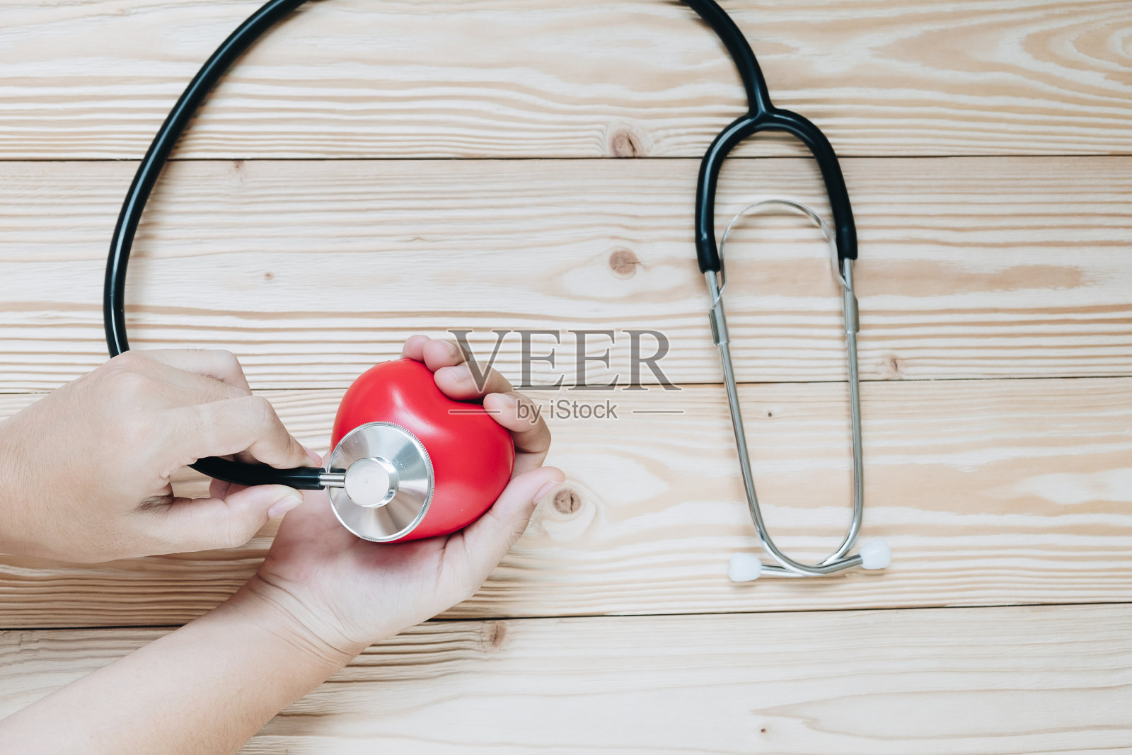 手持听诊器，红色心形，木质背景。医疗保健和保险概念照片摄影图片
