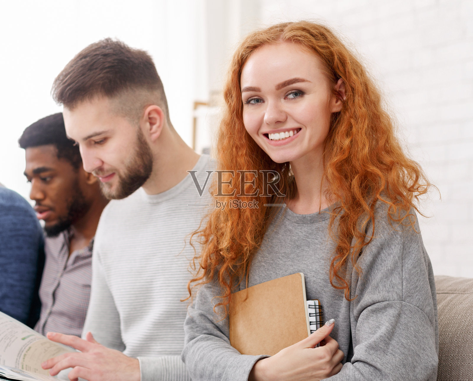 女孩对着镜头微笑，和朋友在家里学习照片摄影图片