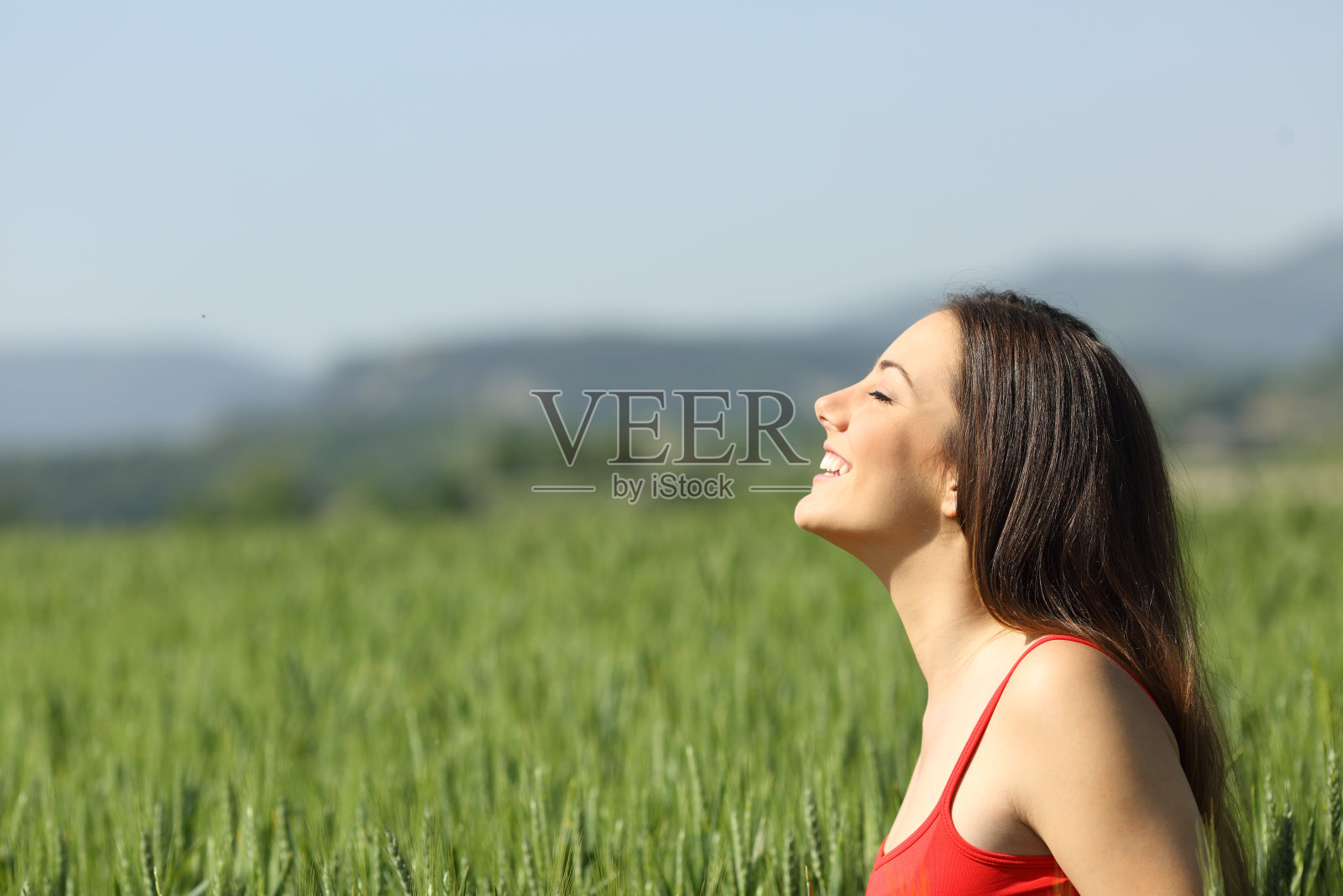 红色的快乐女人呼吸着田野里的新鲜空气照片摄影图片