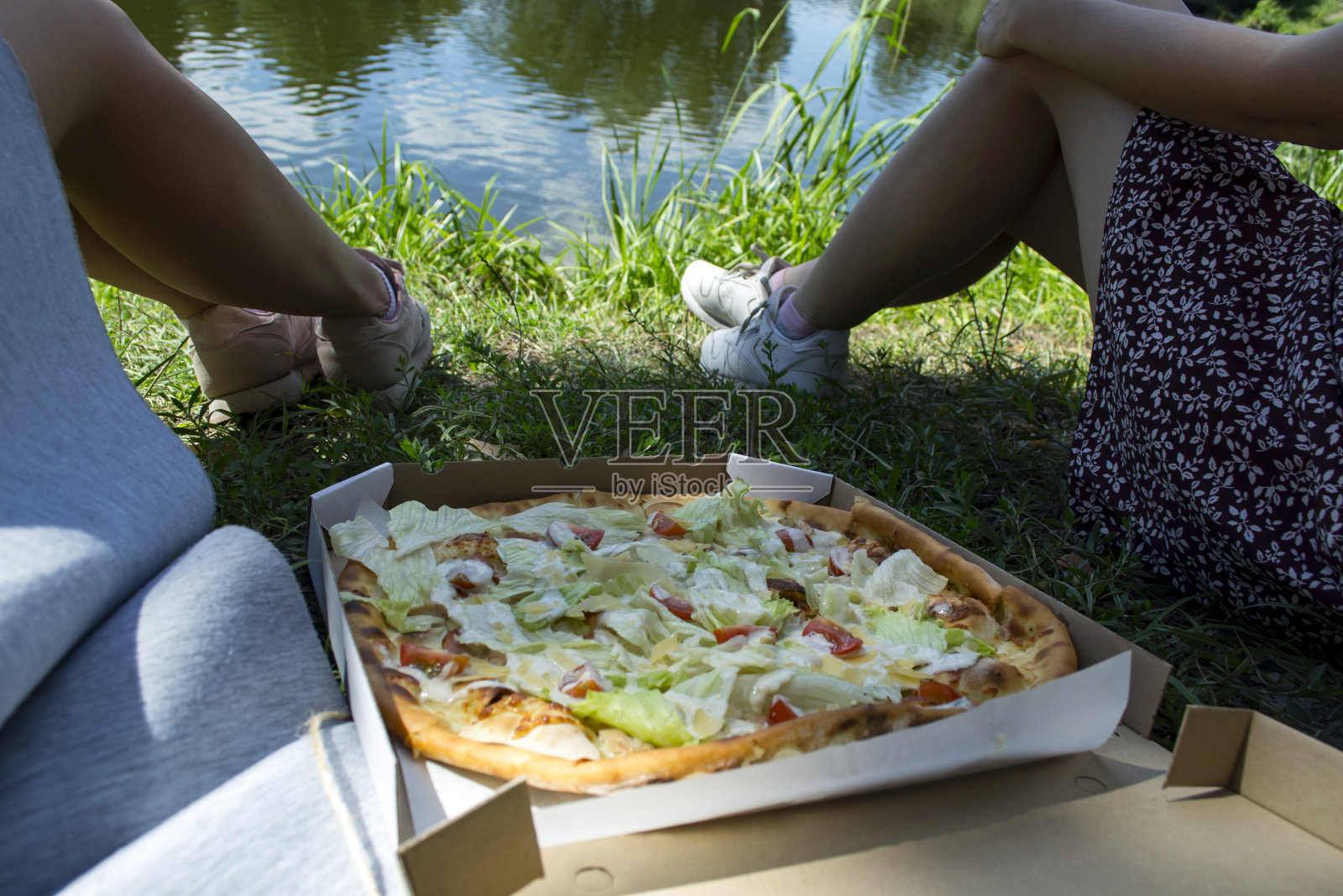 朋友们在湖边吃披萨。照片摄影图片