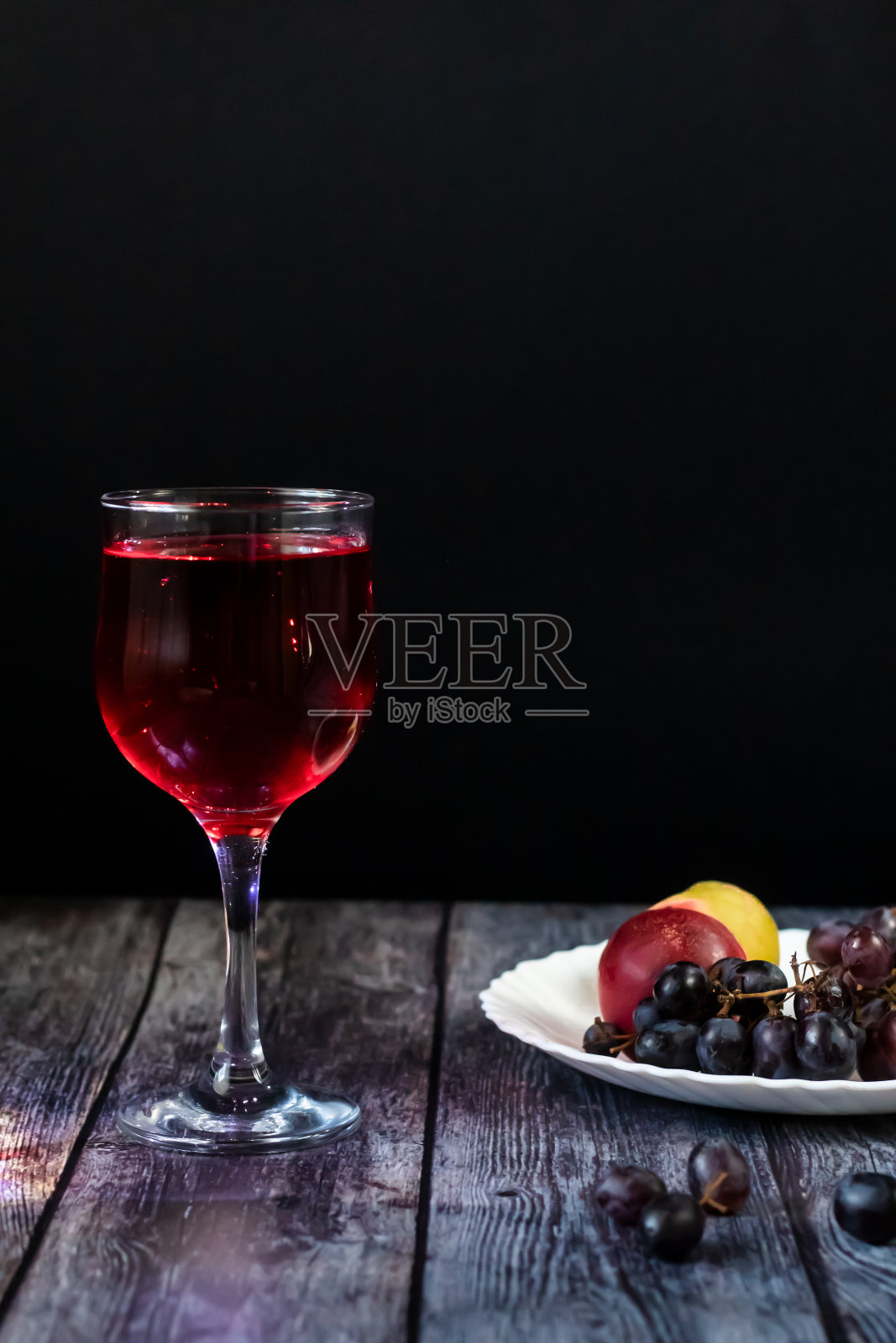 粉红葡萄酒。在水果和葡萄旁边的玻璃杯里的葡萄酒。传统格鲁吉亚葡萄酒根据古老的技术。复制空间关闭和垂直方向。照片摄影图片