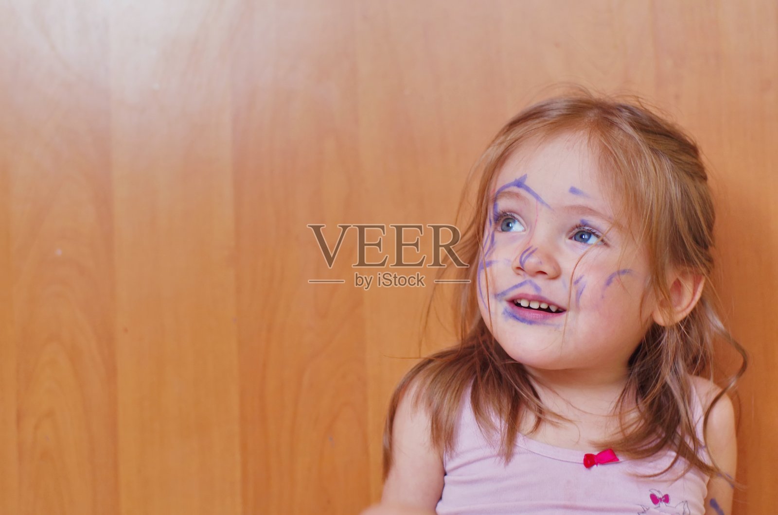 一个有趣的3岁女孩的肖像，用毡尖笔画了一张脸。小爱开玩笑的人照片摄影图片