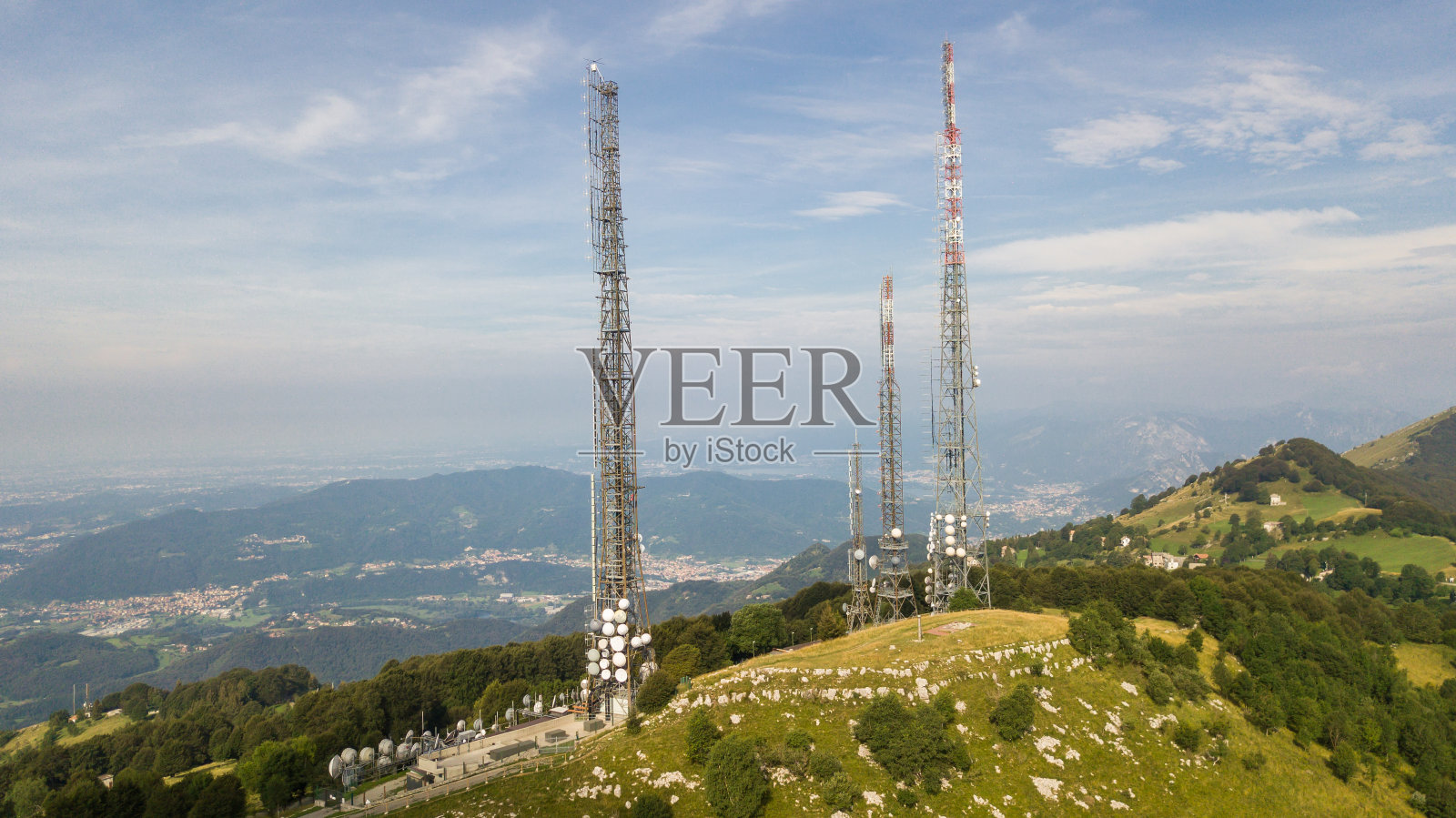 无人机鸟瞰图，一组通信塔，电视广播，手机，无线电和卫星在林带山顶。电磁和环境污染。意大利阿尔卑斯山照片摄影图片