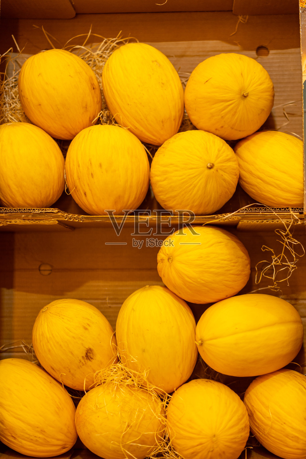 多汁漂亮的黄色甜瓜躺在商店货架上的一个纸箱里。照片摄影图片