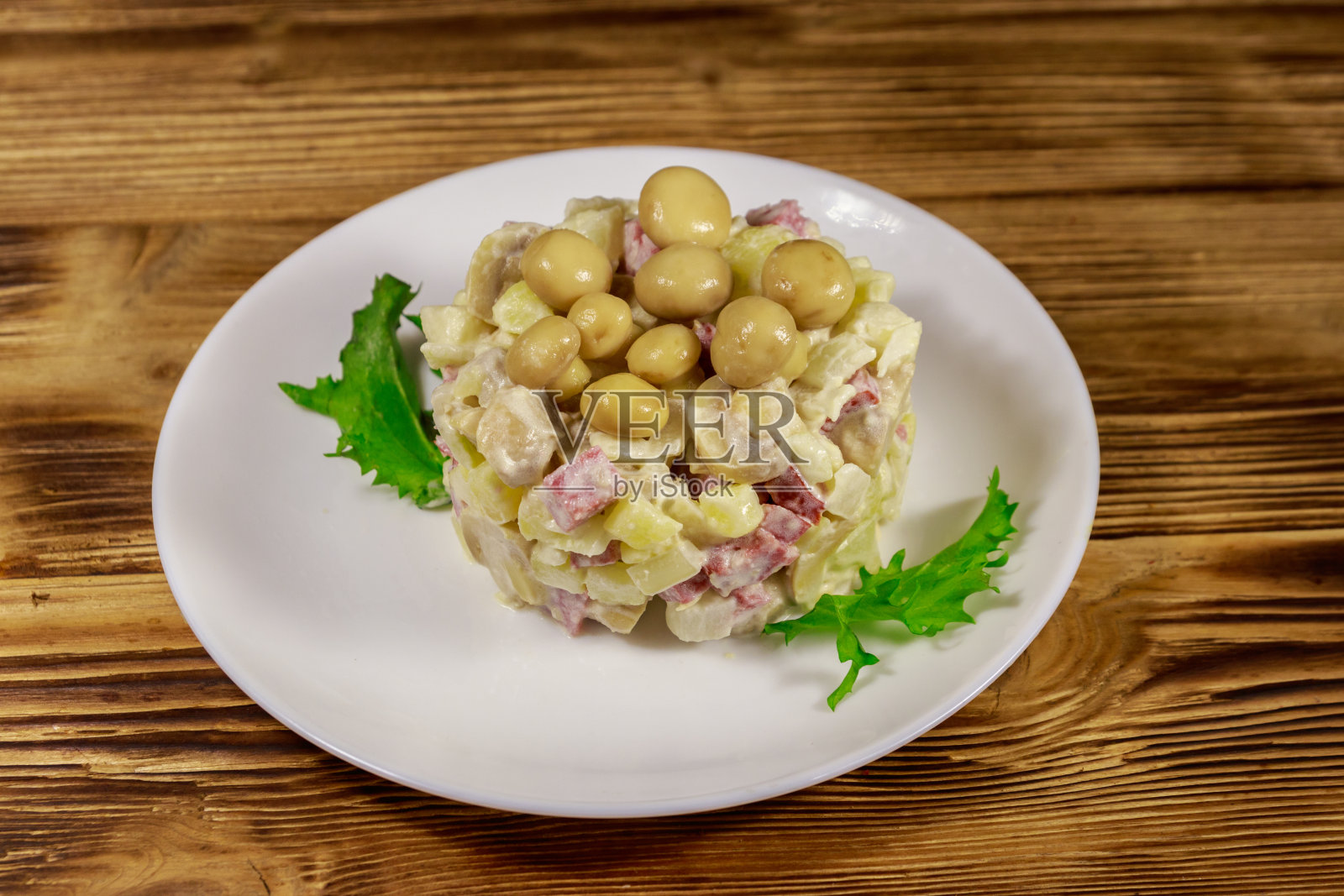 木桌上的土豆沙拉配腌蘑菇、香肠、洋葱和蛋黄酱照片摄影图片