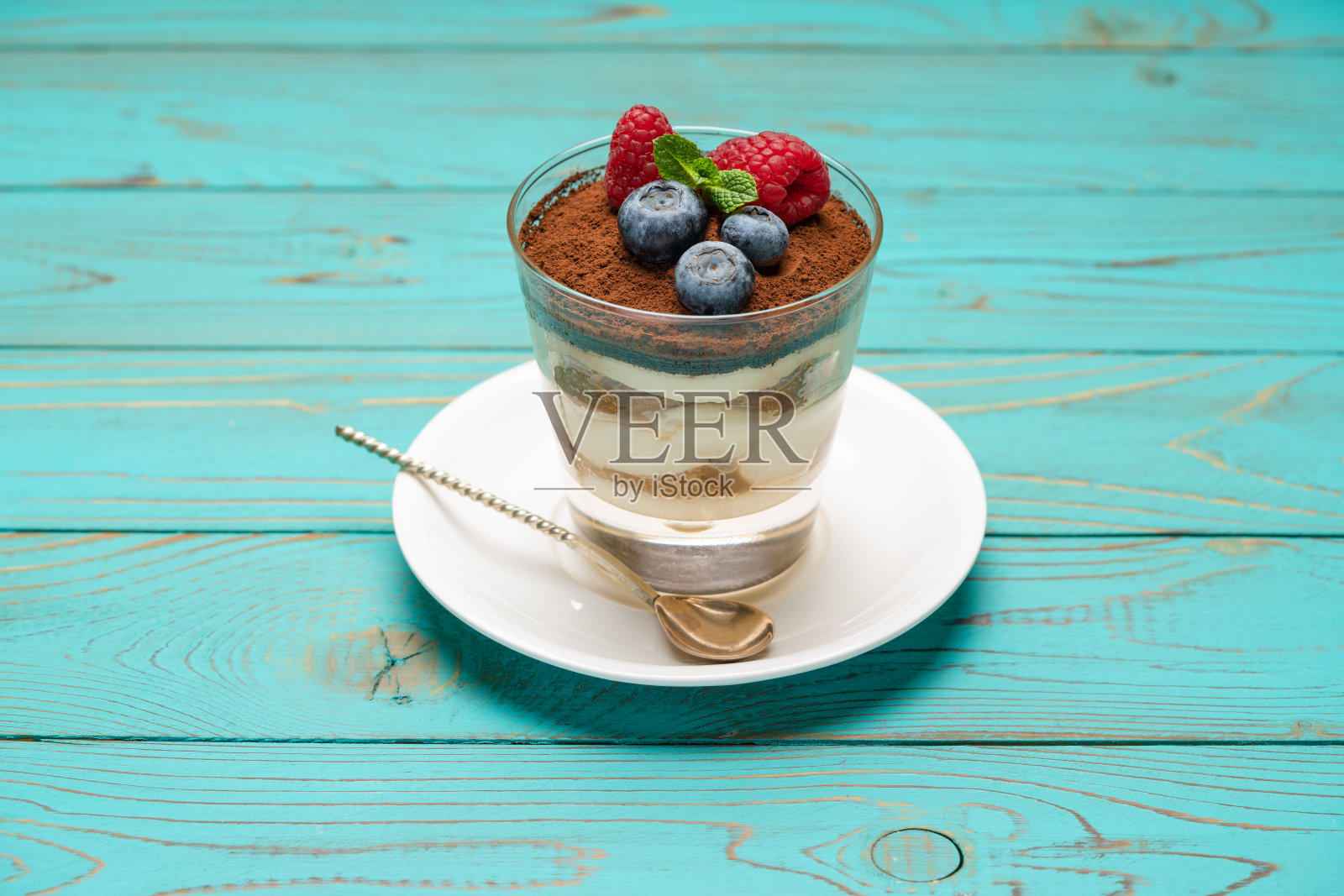 经典的提拉米苏甜点，蓝莓和草莓放在玻璃杯里，木质背景照片摄影图片