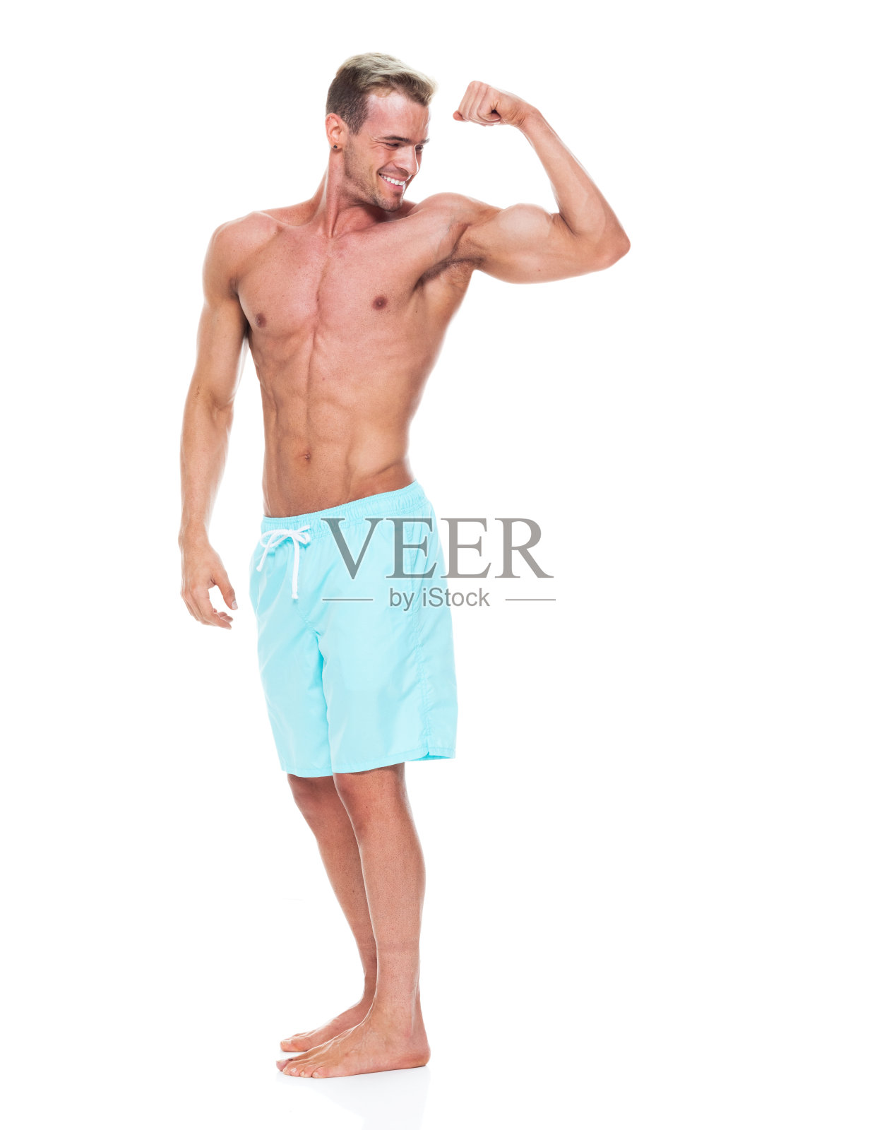 英俊的肌肉男子谁是赤膊和穿着板短裤和弯曲他的肌肉照片摄影图片