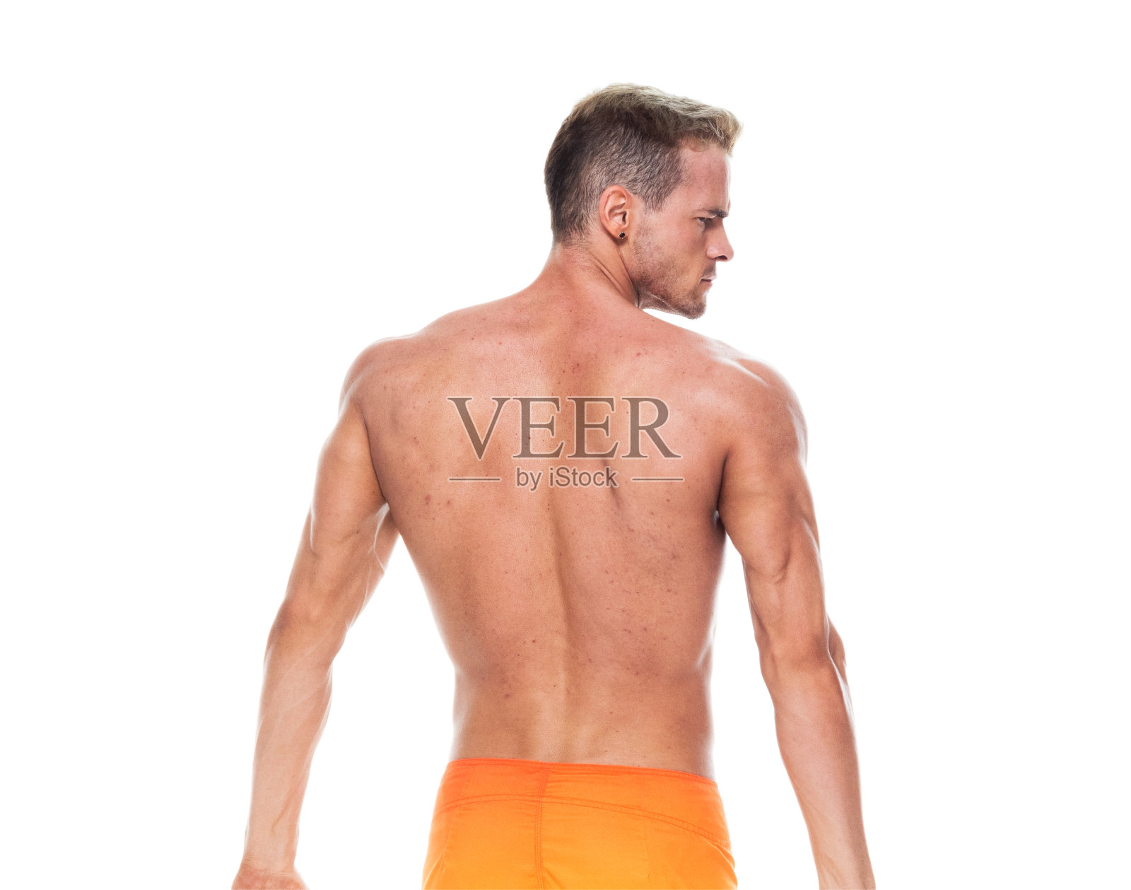 英俊的肌肉男子谁是赤膊和穿着板短裤和弯曲他的肌肉照片摄影图片