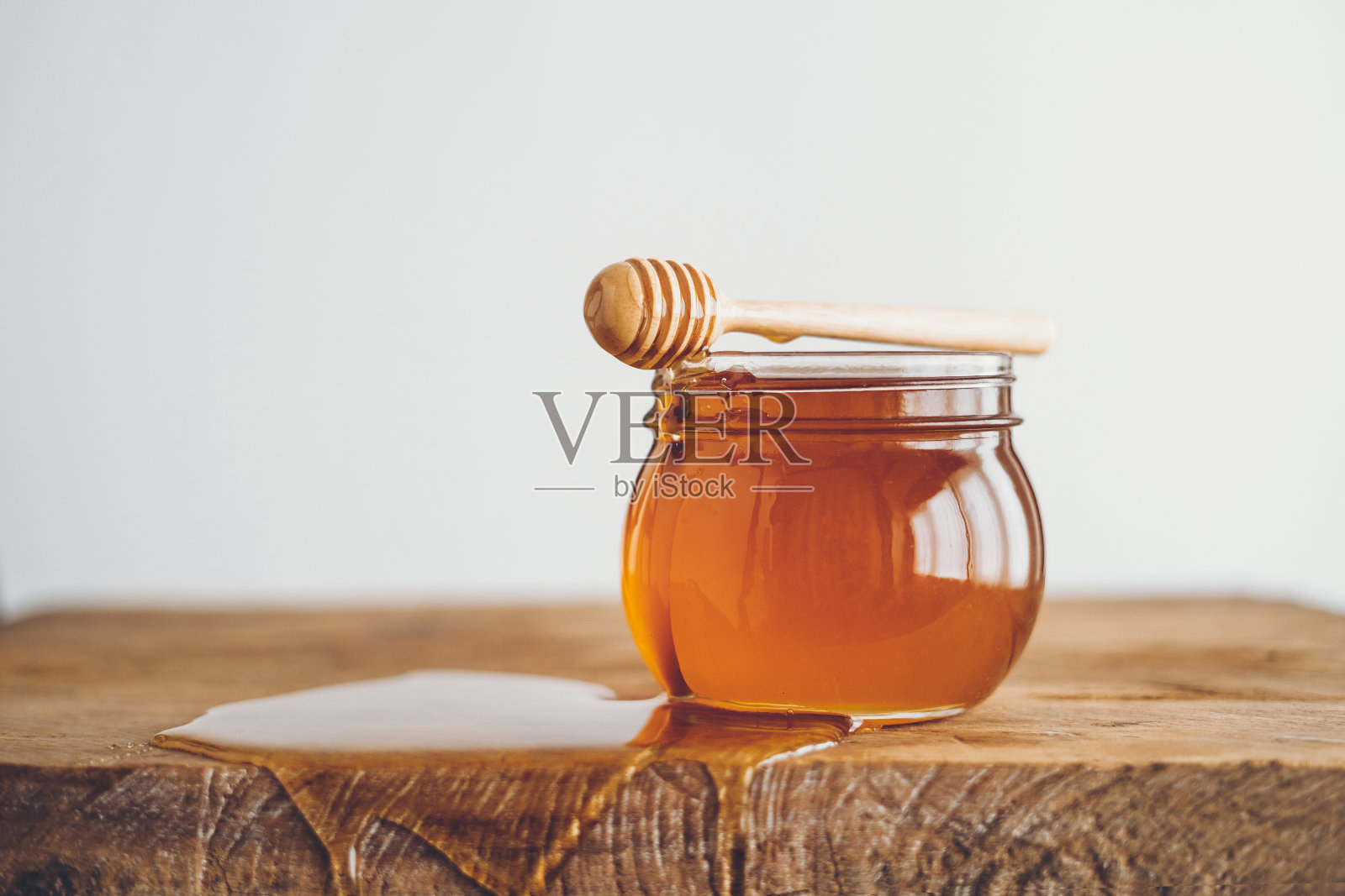 蜂蜜在一个玻璃杯和蜂蜜勺白色的背景照片摄影图片