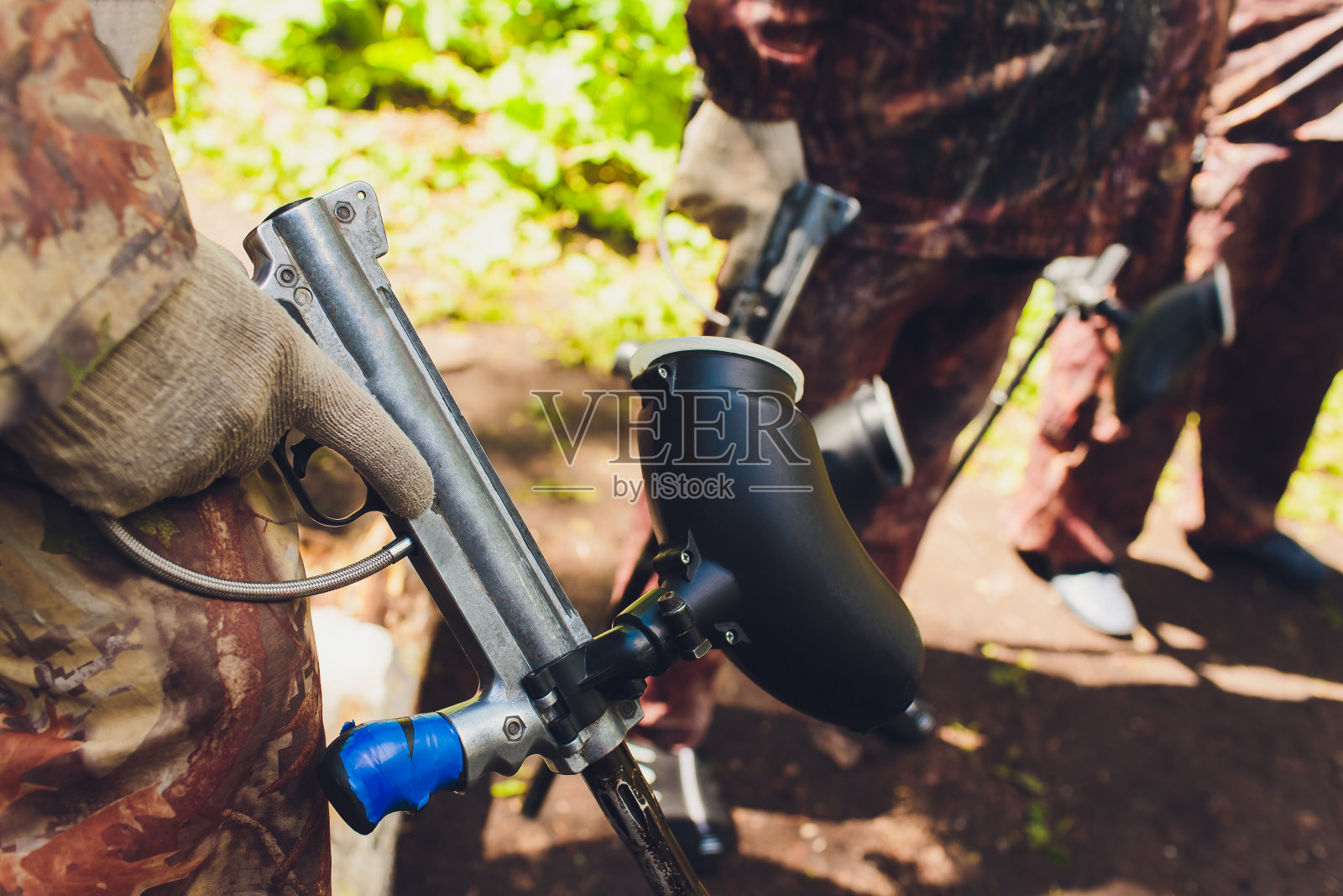 一名身穿迷彩服的男子举着他的彩弹枪站在彩弹区，眼睛直视前方。照片摄影图片