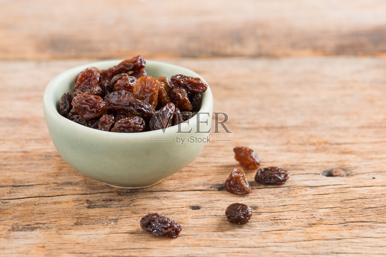 木质背景上的葡萄干。照片摄影图片