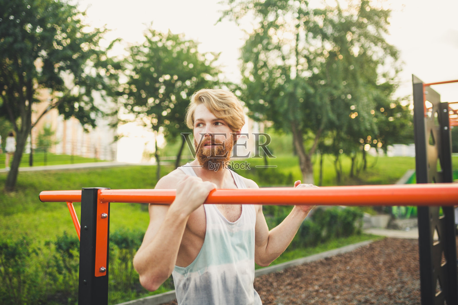 肖像年轻的胡子男子站在公共运动场和训练双杠。英俊的运动的运动员。肖像运动男子的胡子，休息训练后。夏季户外运动照片摄影图片