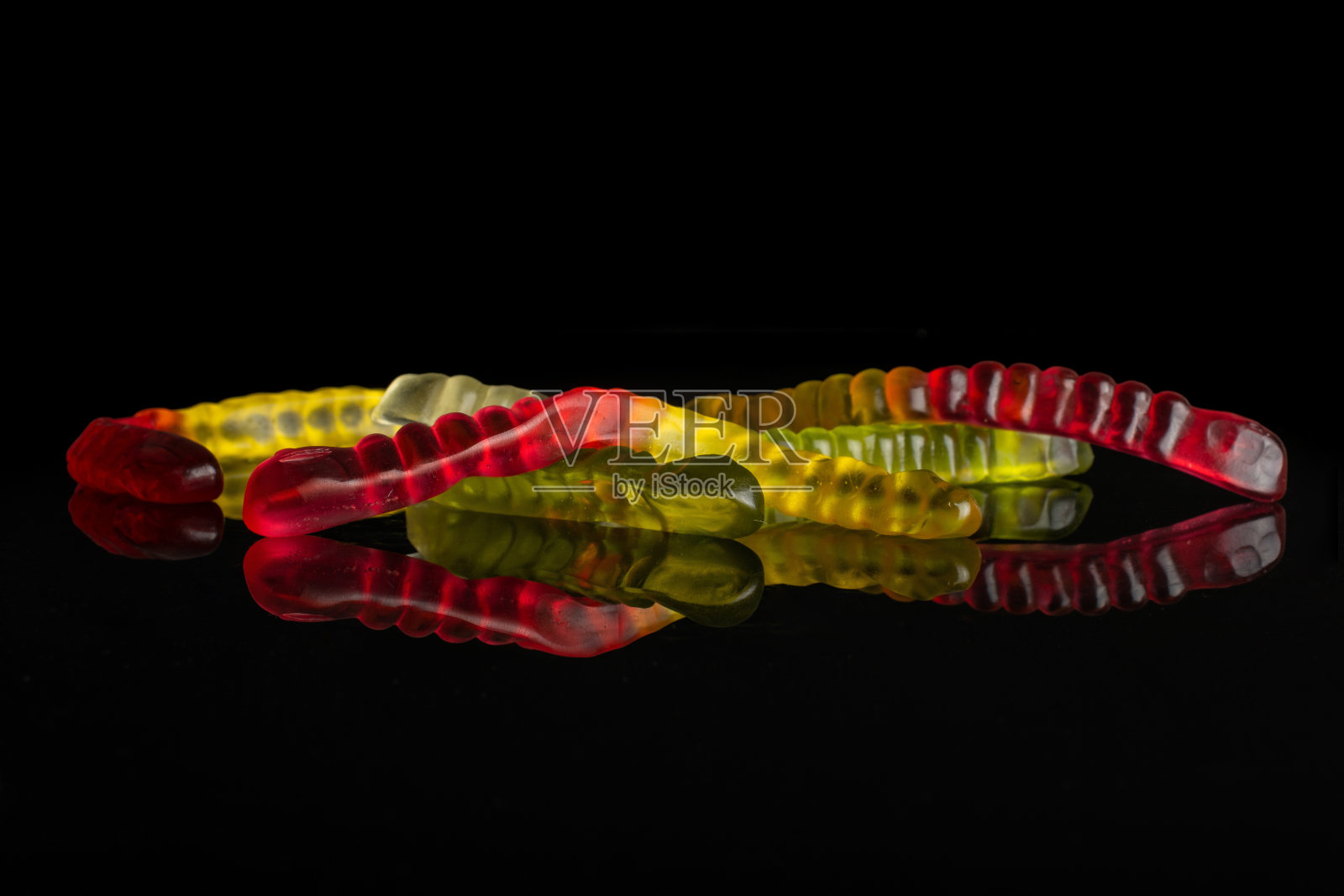 果冻虫糖孤立在黑色玻璃上照片摄影图片