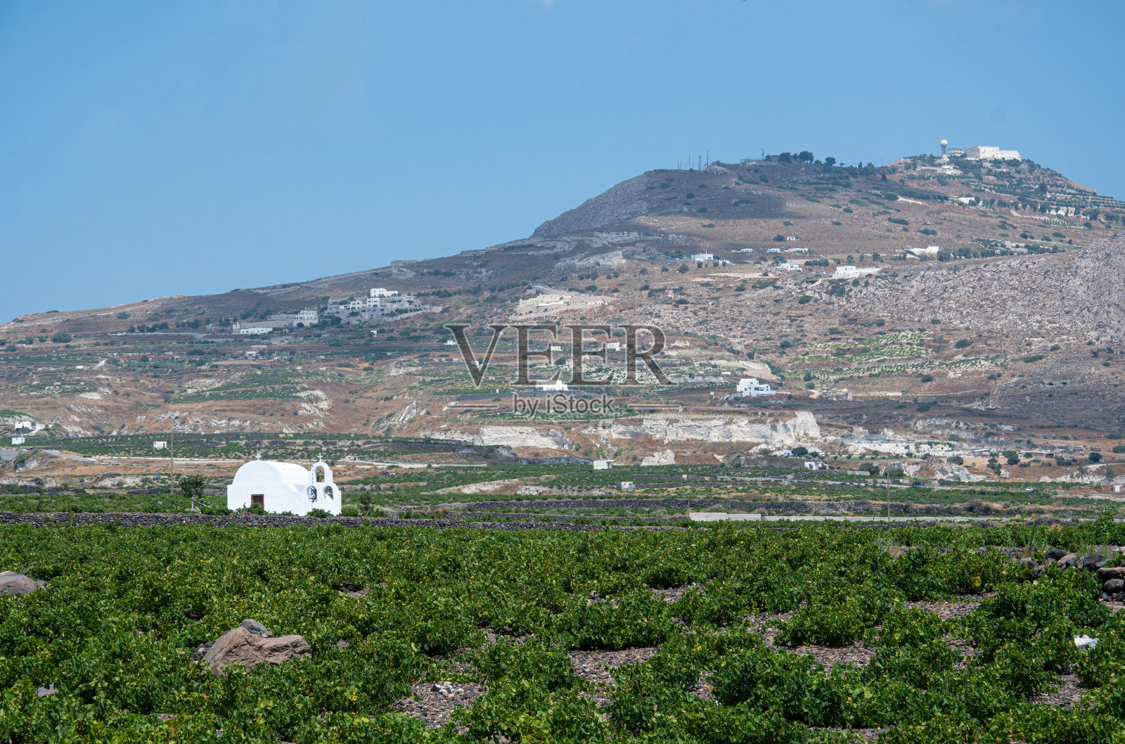 一座粉刷成白色的希腊东正教小教堂坐落在普罗菲提斯山低地的圣托里尼葡萄园之间照片摄影图片
