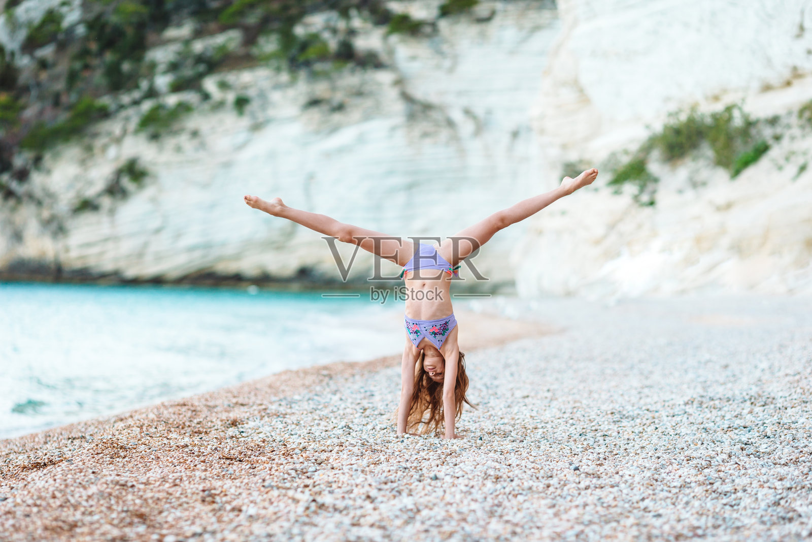 活泼的小女孩在海滩上玩得很开心。可爱的孩子在海边做运动照片摄影图片