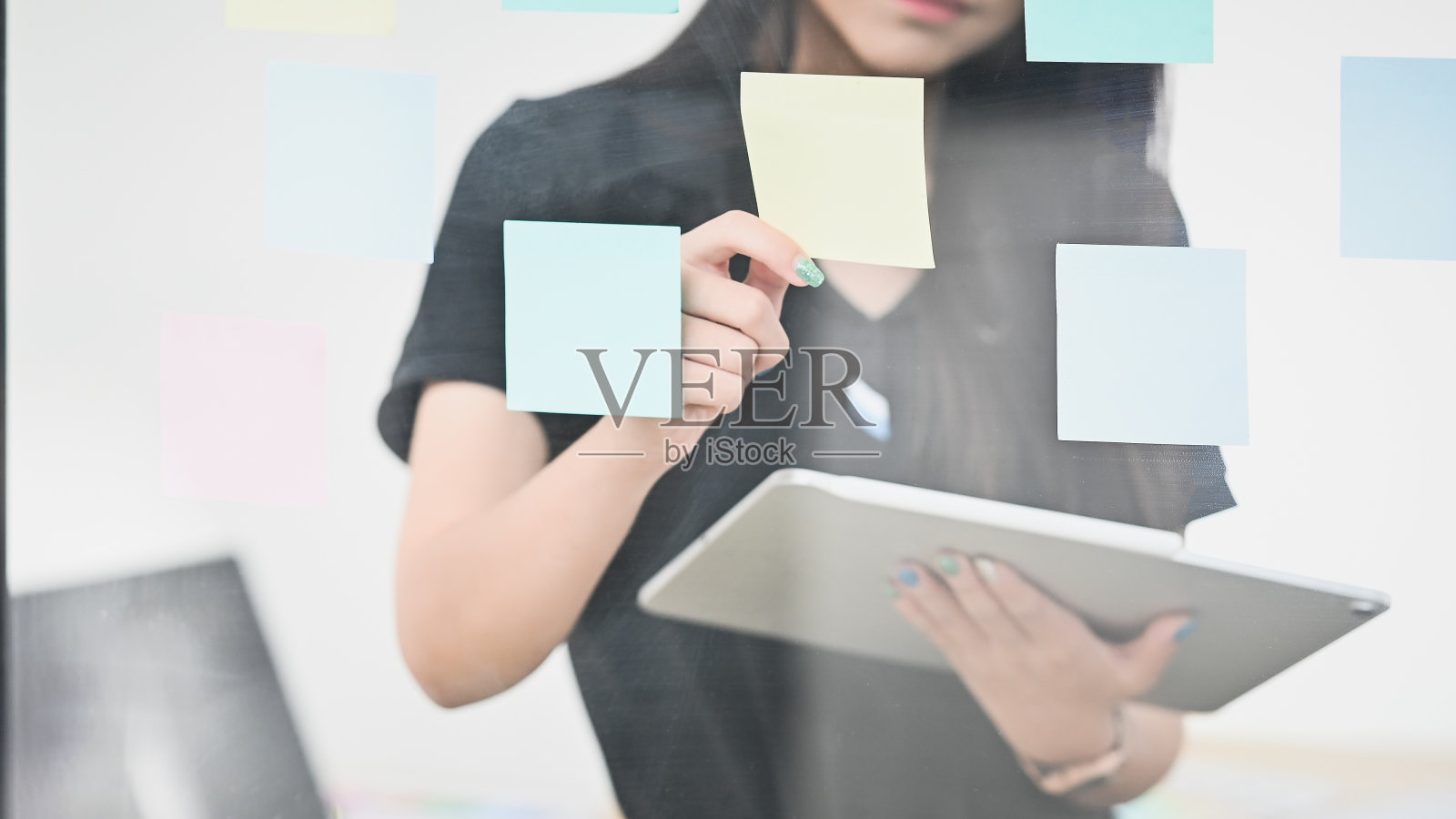 拿着便利贴和平板电脑的女人。照片摄影图片