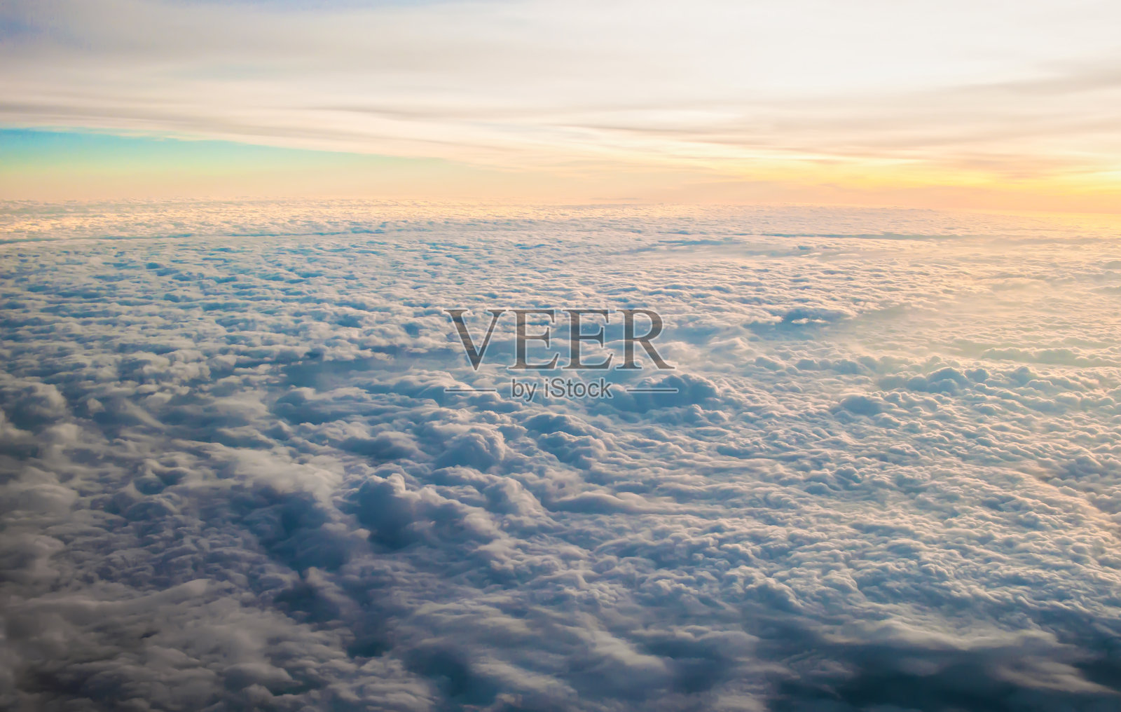 在温暖的黄色灯光下，日出时许多白色蓬松的云，如梦似幻。地平线上的蓝天。在晴朗无云的日子里乘飞机旅行。游移和荣华的感觉照片摄影图片