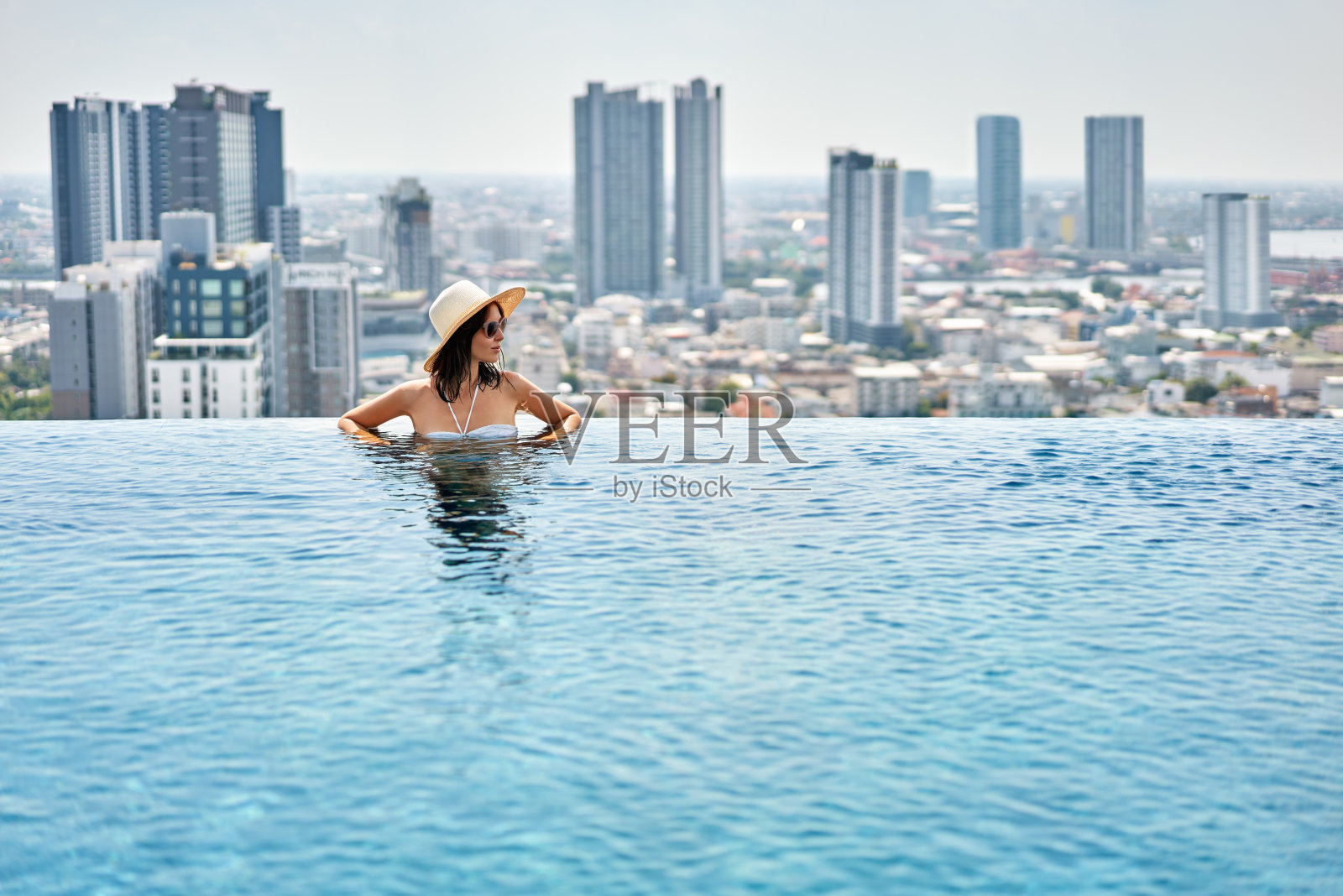 年轻女子在屋顶游泳池里享受暑假照片摄影图片