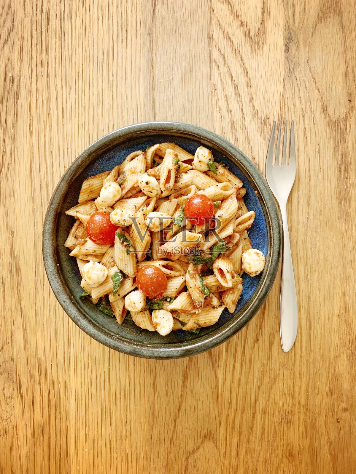 素食意大利面，配樱桃番茄、马苏里拉奶酪、菠菜和罗勒照片摄影图片