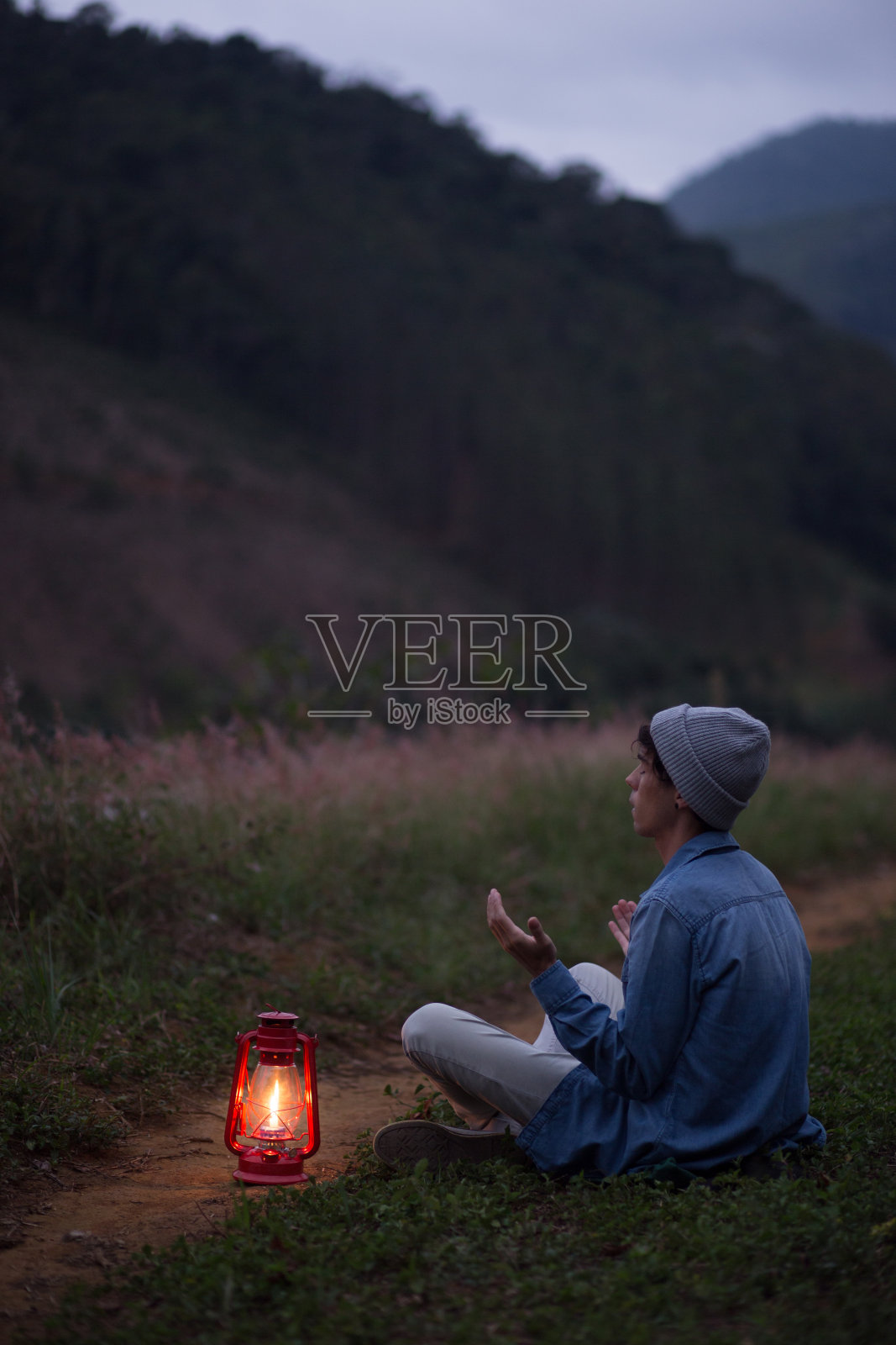 一个小男孩提着露营灯坐在草地上照片摄影图片