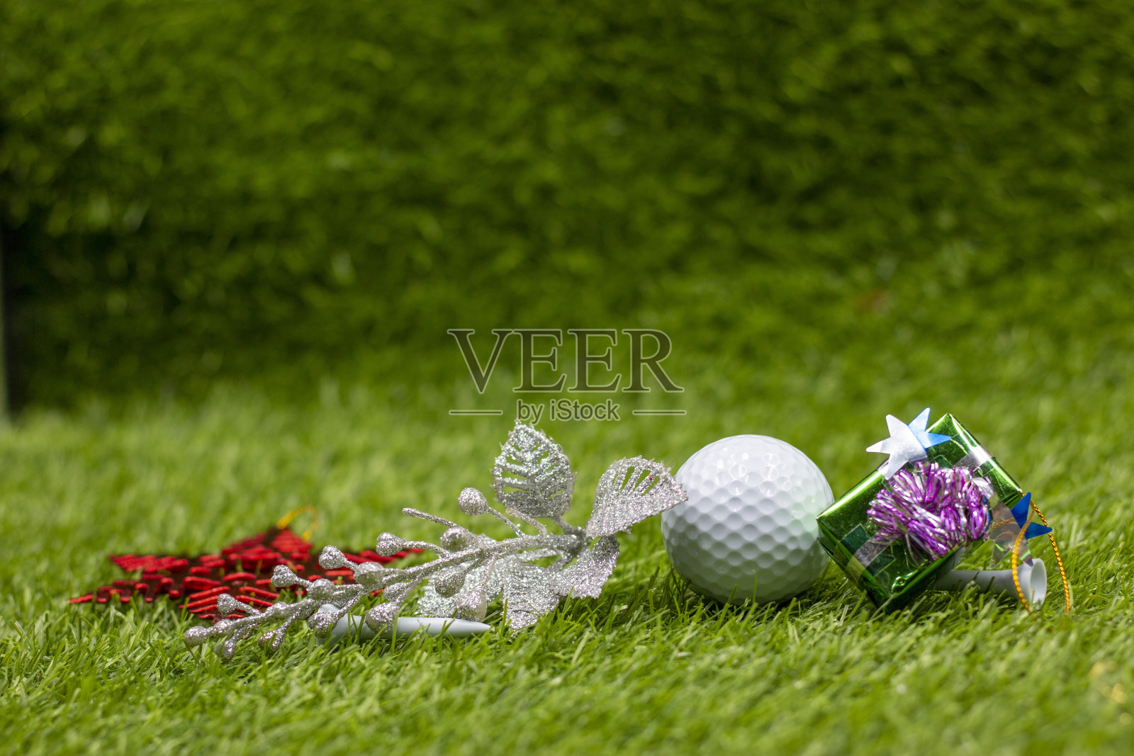 祝高尔夫球手圣诞快乐，绿草地上有高尔夫球和圣诞装饰品照片摄影图片
