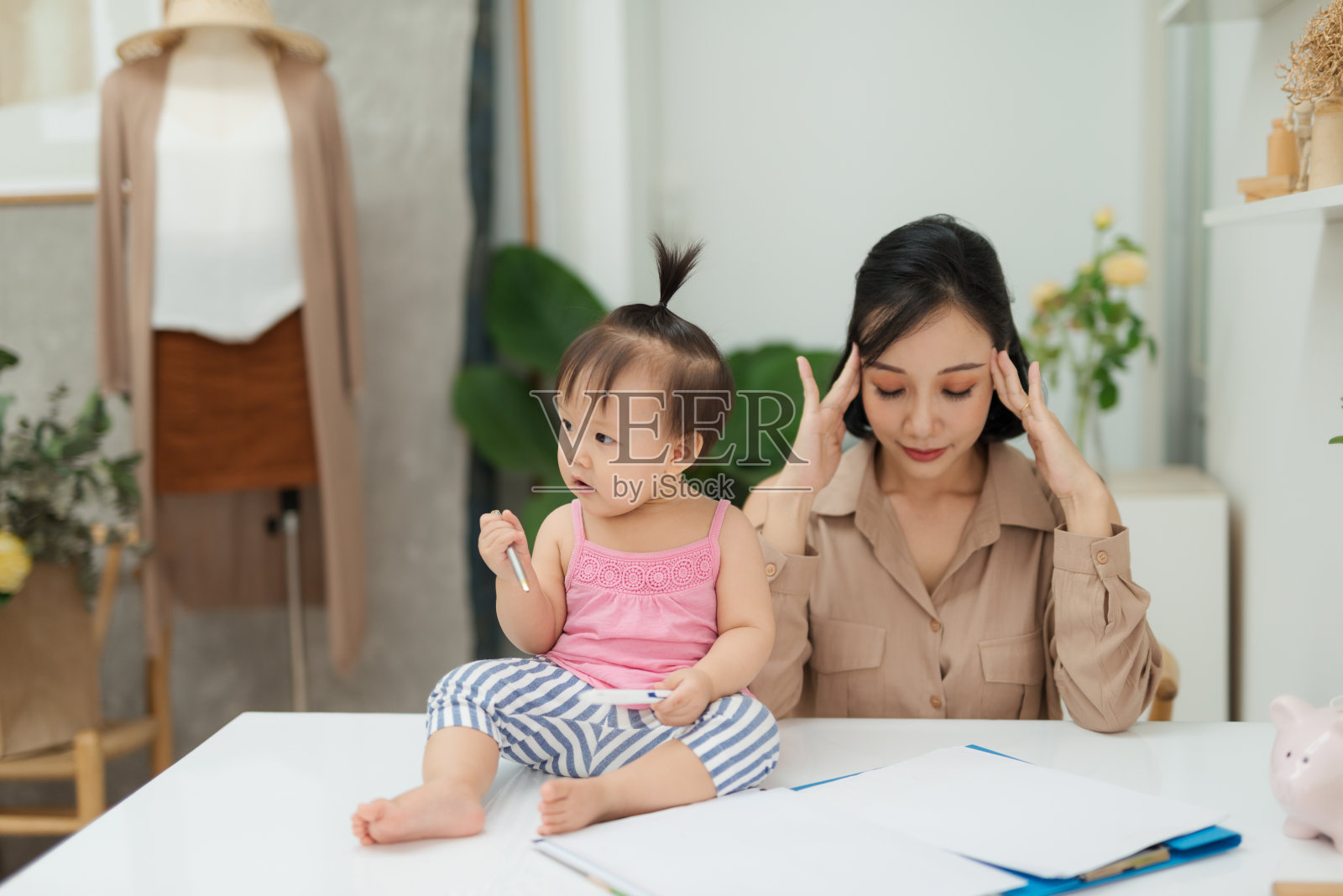 我妈妈是真正的专家!小女孩坐在办公室的桌子上看着相机，她的妈妈在办公室照片摄影图片