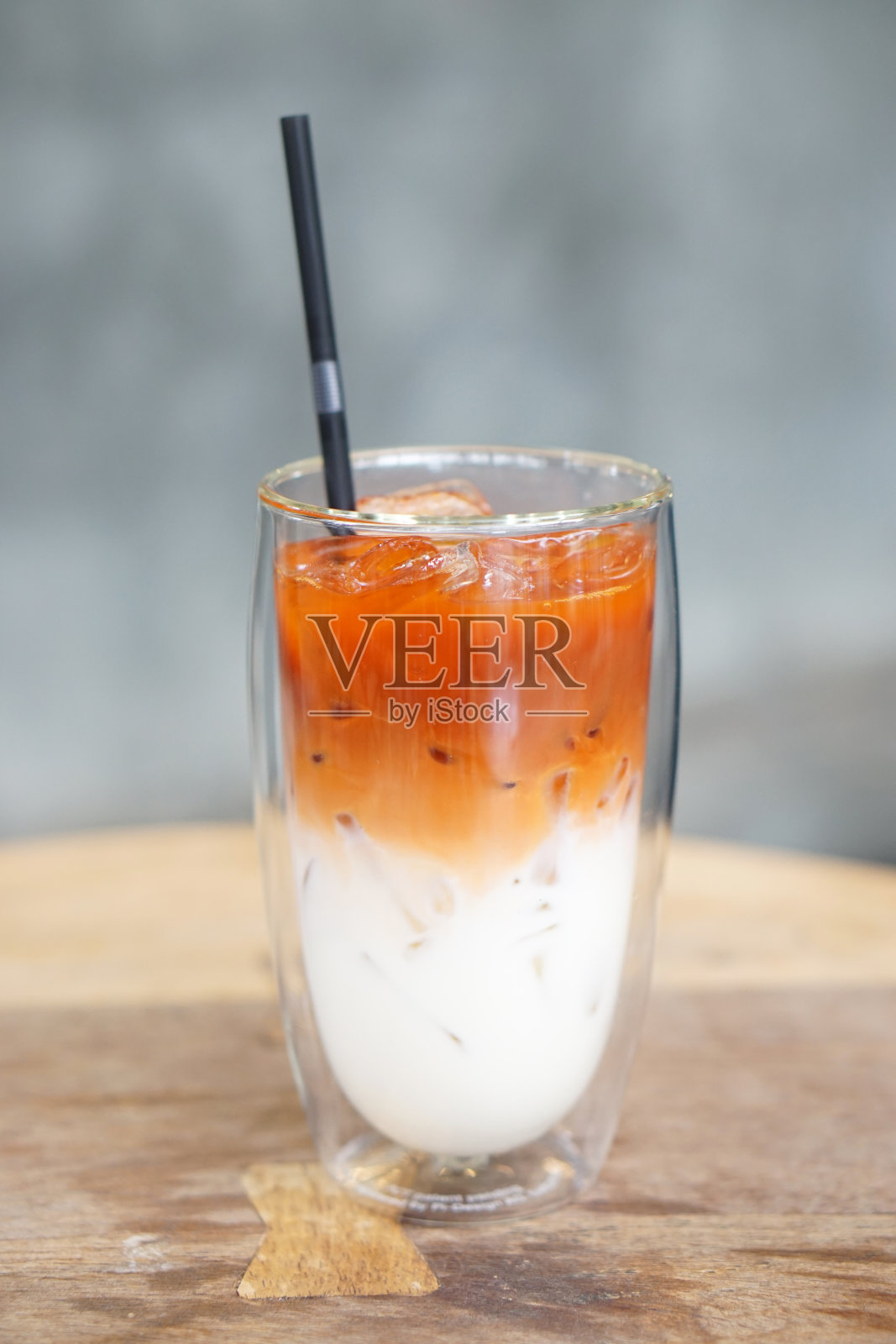 冰奶茶-一杯混合了新鲜牛奶的泰国茶在桌子上和模糊的背景。照片摄影图片