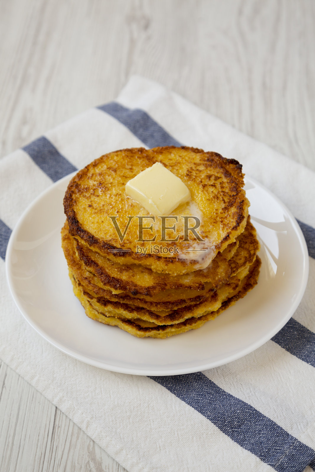 自制玉米粉约翰尼蛋糕与黄油在一个白色盘子，低角度观看。特写镜头。照片摄影图片