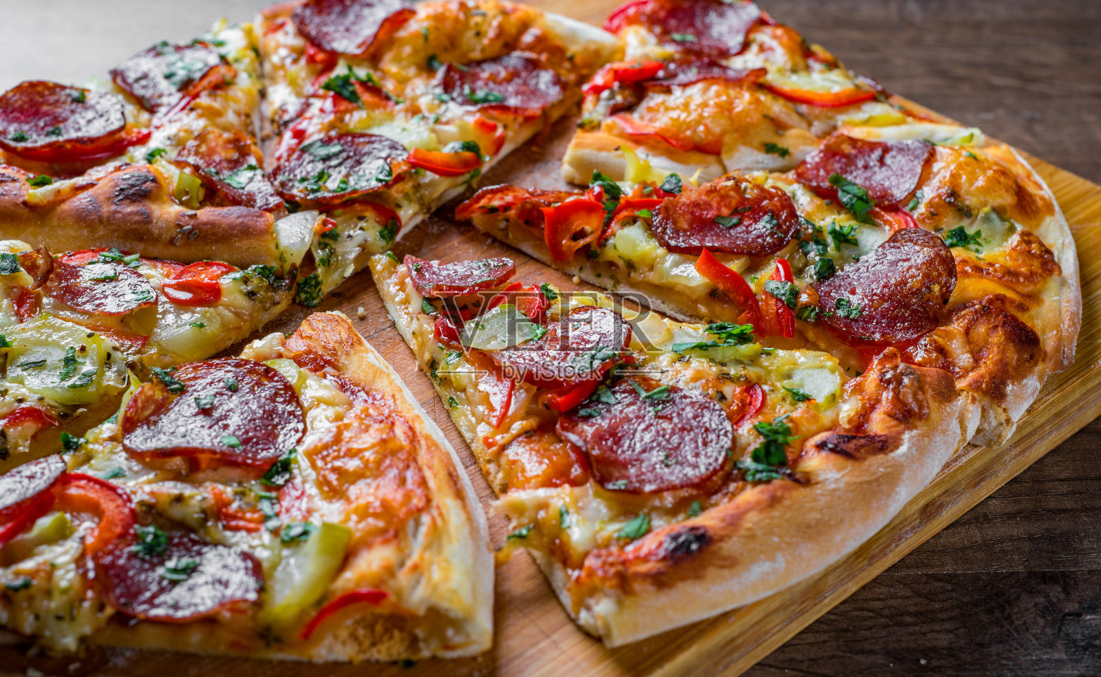 意大利辣香肠披萨配马苏里拉芝士，意大利腊肠，胡椒。香料和新鲜罗勒。木桌子上的意大利披萨照片摄影图片