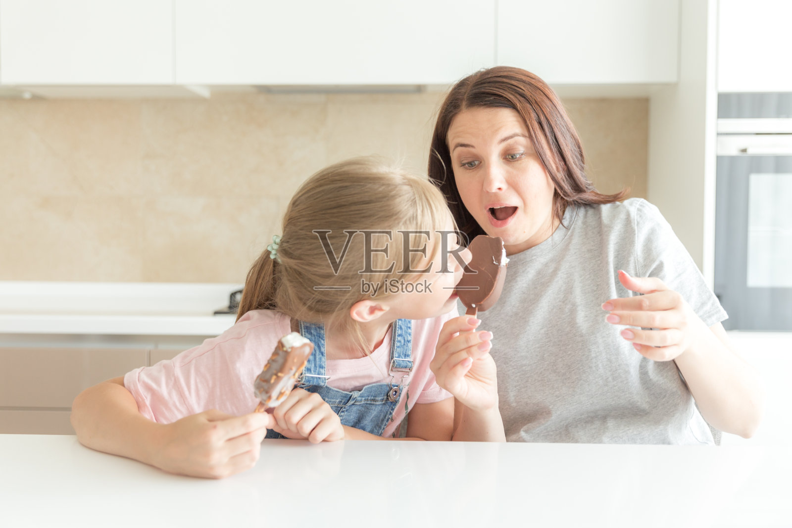 母亲和女儿在厨房吃冰淇淋。良好的亲子关系。幸福的家庭的概念照片摄影图片