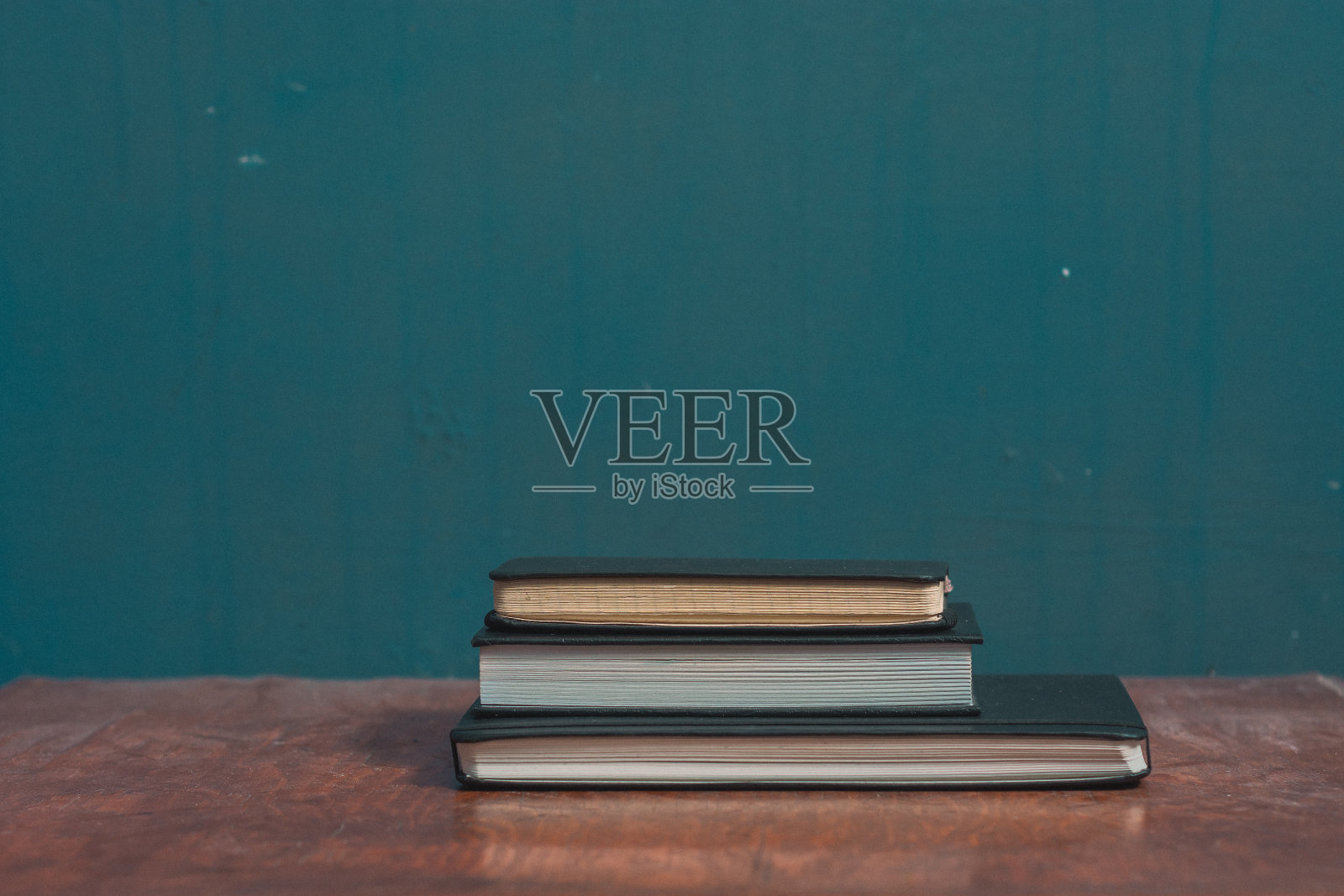 三个封闭的笔记本放在木桌上照片摄影图片