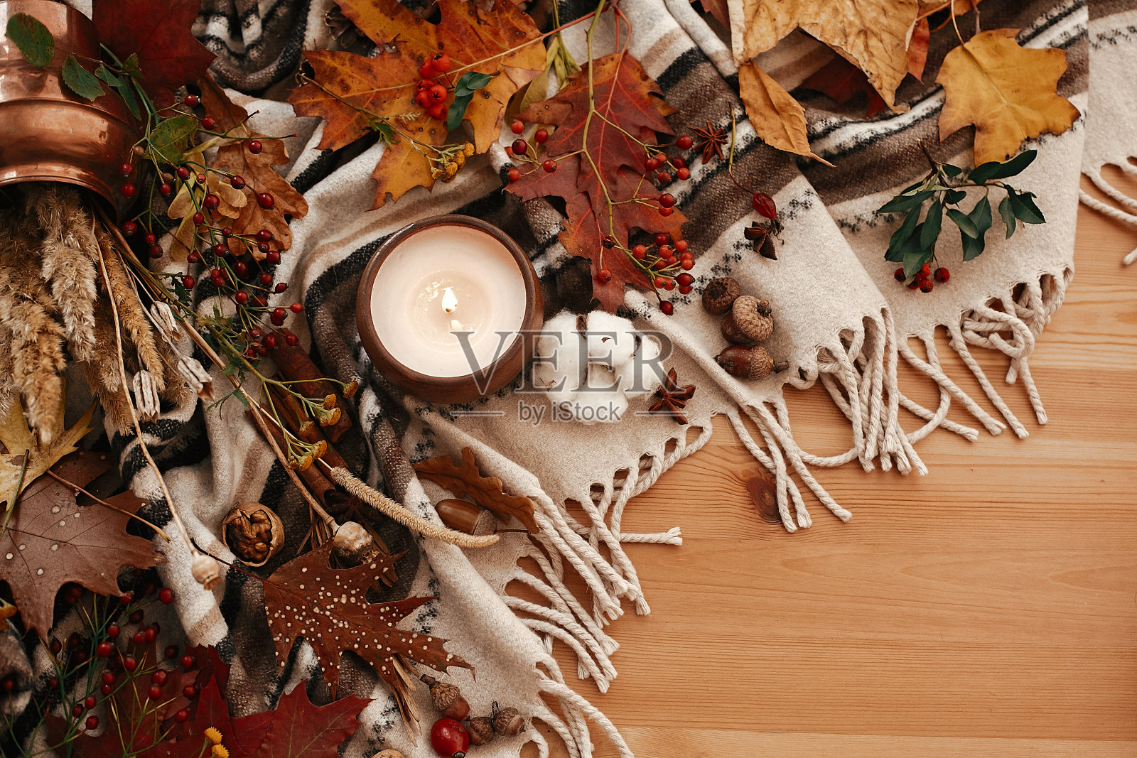 秋平。舒适的生活方式，舒适的心情。蜡烛与浆果，落叶，茴香，香草，橡子，坚果，肉桂，棉花在棕色毯子。你好,秋天照片摄影图片