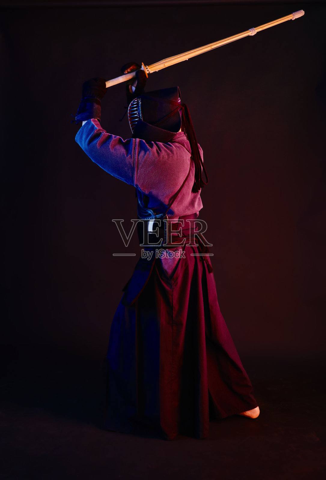 近景，剑道战士穿着盔甲，传统和服，头盔练习武术与shinai竹剑，黑色背景照片摄影图片