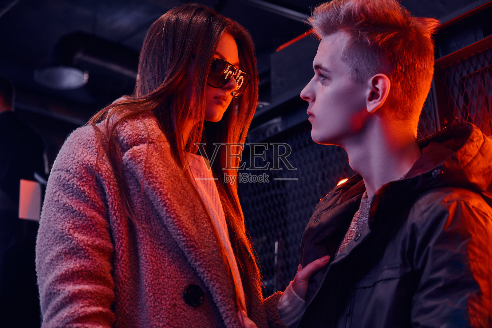 一对年轻时尚的夫妇站在咖啡馆里激情地看着对方，咖啡馆内部是工业风格的，背景是背光招牌照片摄影图片