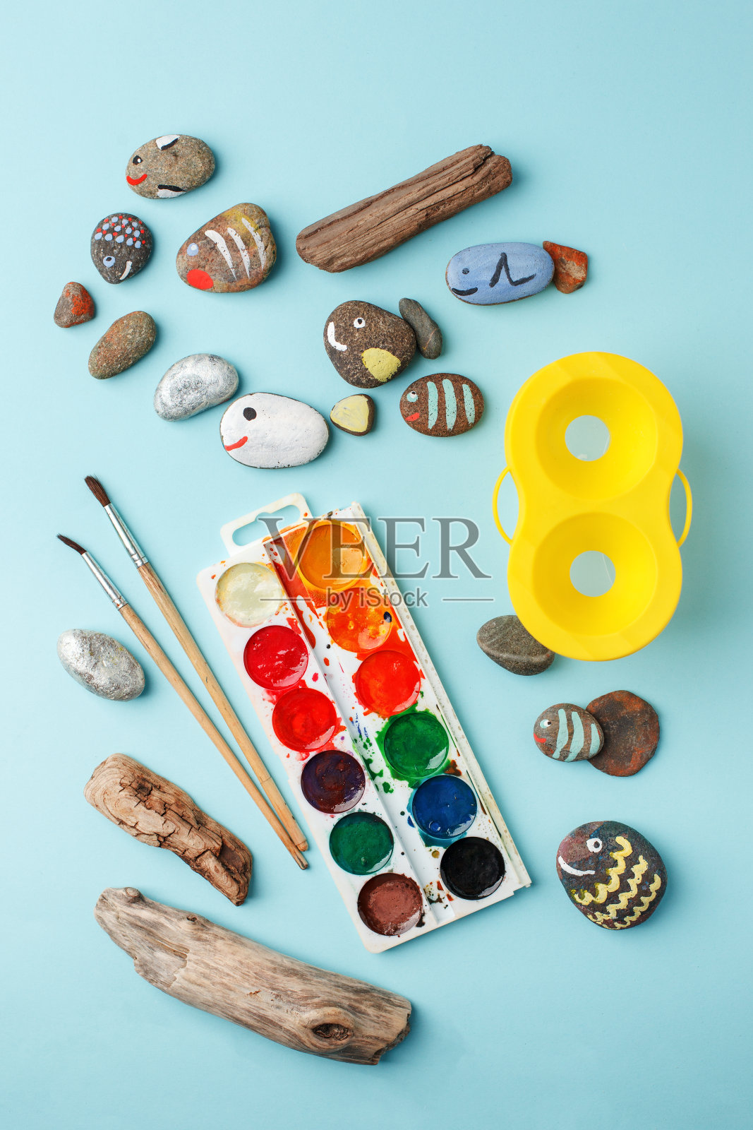 蓝色桌子上有手绘的七彩石头和水彩颜料。石画。DIY、幼儿园、日托创意艺术、爱好概念照片摄影图片