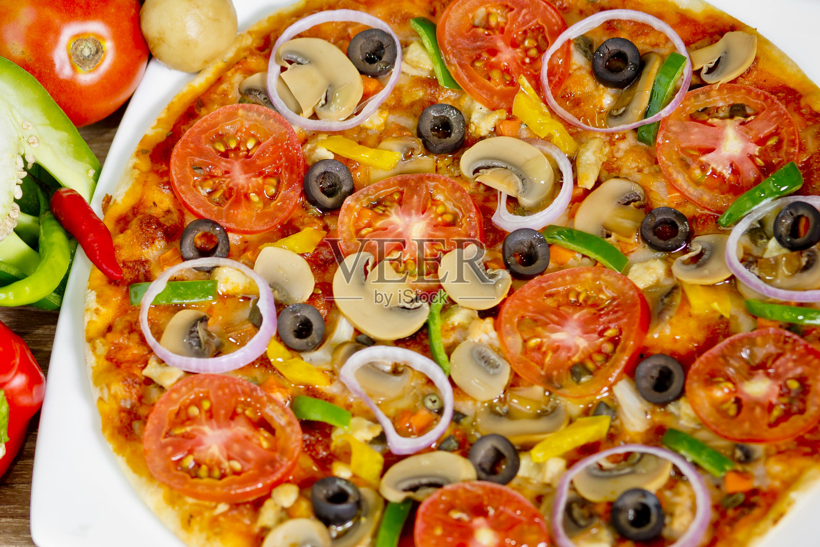 流行的彩色配料如西红柿、奶酪、蘑菇、辣椒、橄榄和其他配料烘焙健康披萨。照片摄影图片