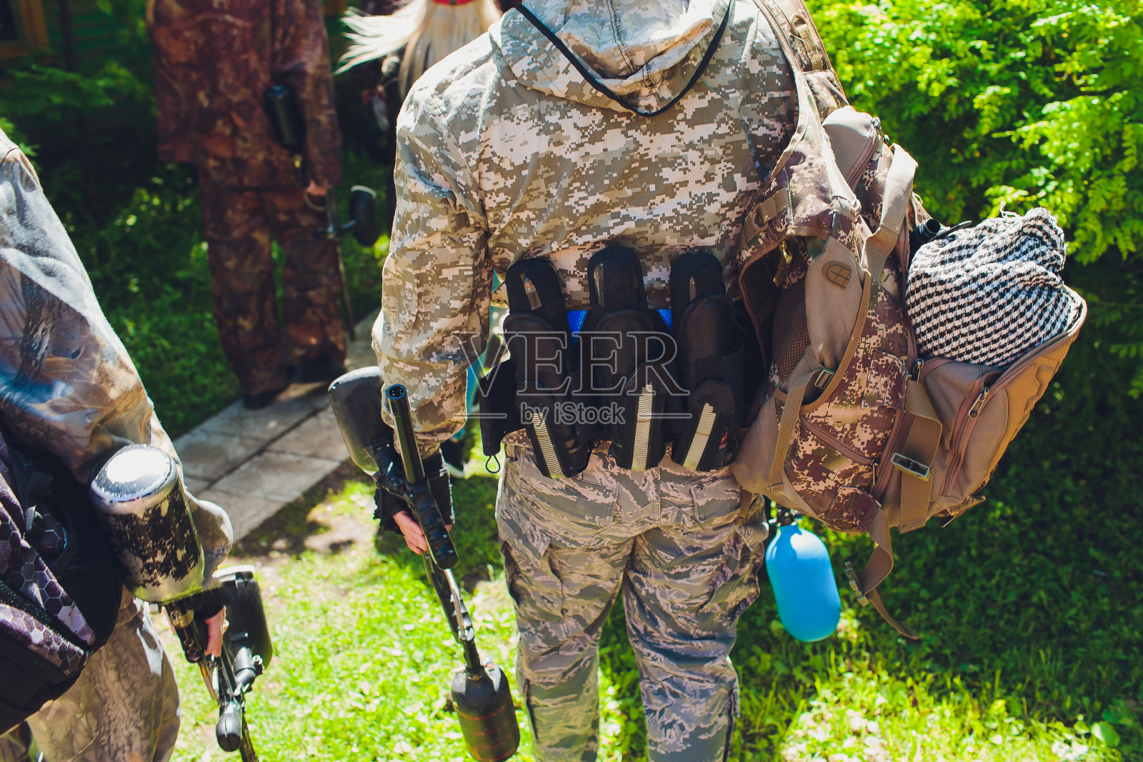 一名身穿迷彩服的男子举着他的彩弹枪站在彩弹区，眼睛直视前方。照片摄影图片