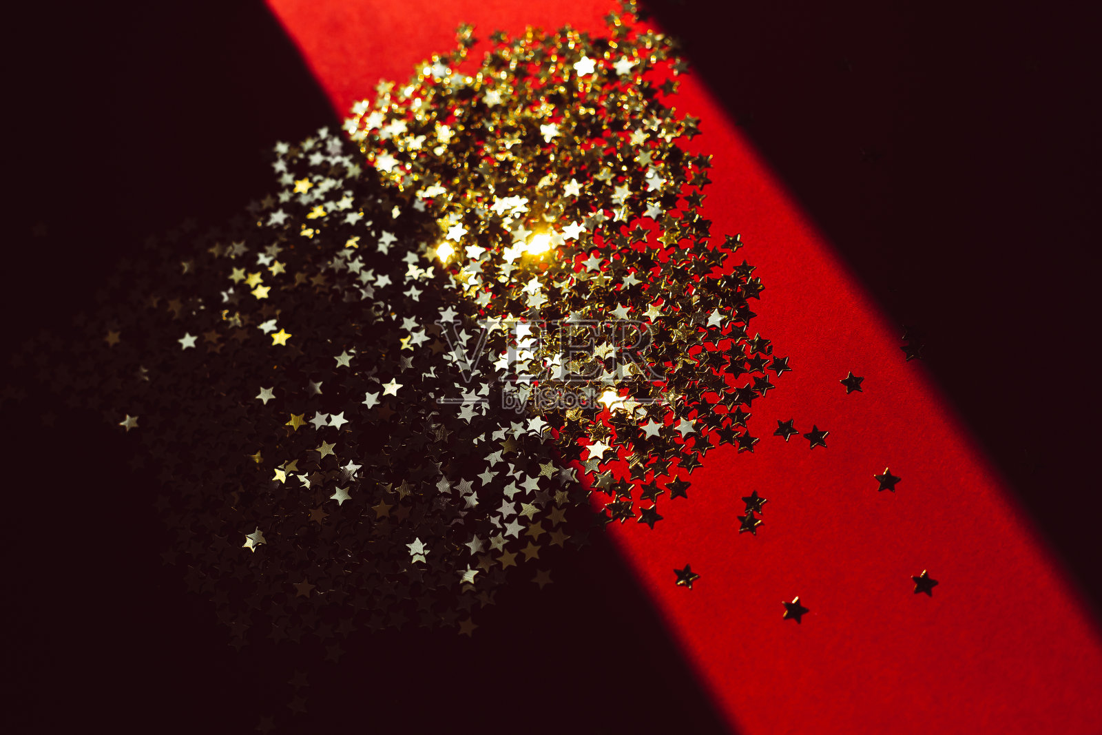 在耀眼的灯光下，金色的星星纸屑和阴影照片摄影图片