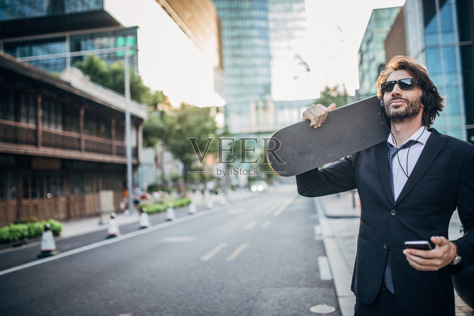 年轻的商人在街上玩滑板照片摄影图片