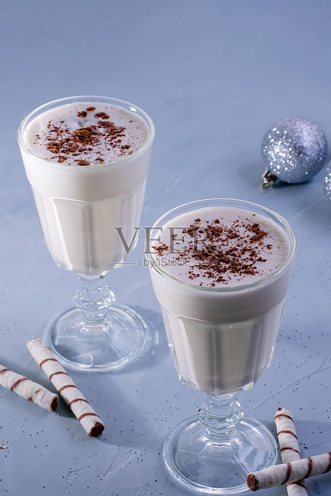 两杯自制的肉桂蛋酒奶昔，蓝色纹理背景上的圣诞装饰。圣诞节的气氛照片摄影图片