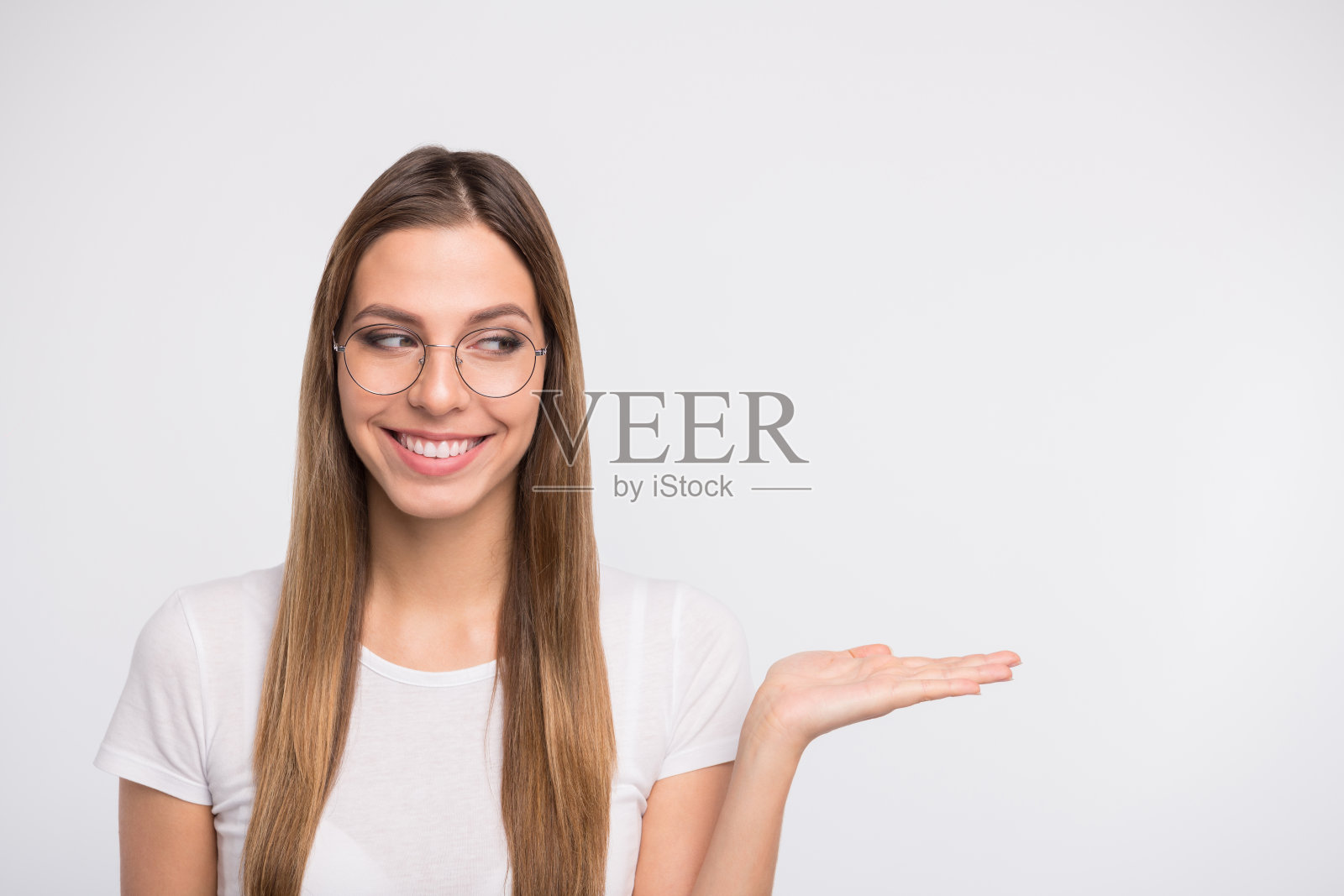 漂亮的女士抱着新产品在开放的手臂上戴眼镜和休闲t恤孤立的白色背景照片摄影图片